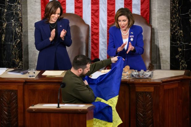 Ukraine's President Volodymyr Zelensky gives a Ukrainian national flag to US House Speaker Nancy Pelosi (D-CA) as US Vice President Kamala Harris (L) looks on during his address the US Congress at the US Capitol in Washington, DC on December 21, 2022. - Zelensky is in Washington to meet with US President Joe Biden and address Congress -- his first trip abroad since Russia invaded in February. (Photo by Mandel NGAN / AFP) (Photo by MANDEL NGAN/AFP via Getty Images)