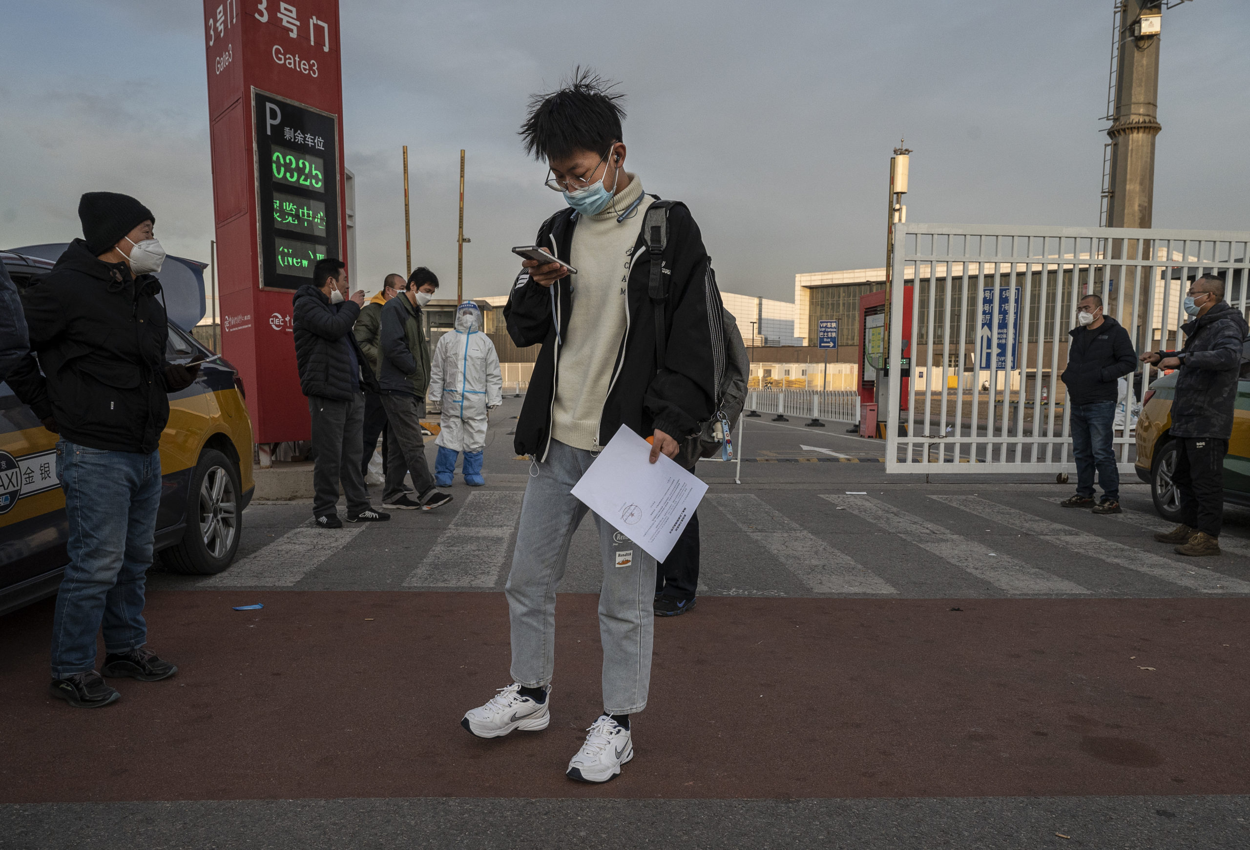 BEIJING, CHINA - DECEMBER 07: A man carries his release papers as he leaves after being released from a government quarantine facility on December 7, 2022 in Beijing, China. As part of a 10 point directive, China's government announced Wednesday that people with COVID-19 who have mild or are asymptomatic will be permitted to quarantine at home instead of being taken to a makeshift facility, a major shift in its zero COVID policy. 