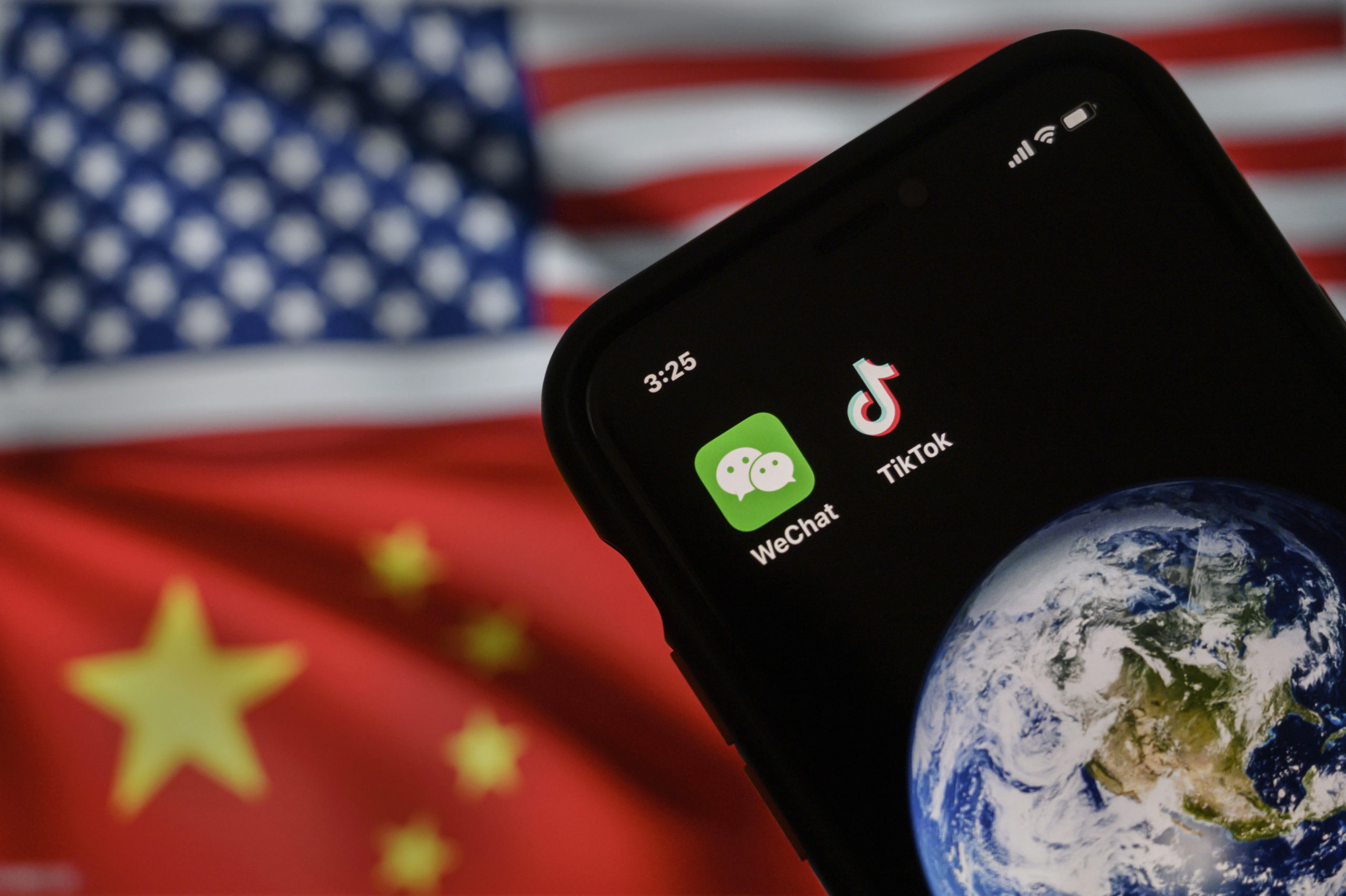 In this photo illustration, a mobile phone can be seen displaying the logos for Chinese apps WeChat and TikTok in front of a monitor showing the flags of the United States and China on an internet page, on September 22, 2020 in Beijing, China. 