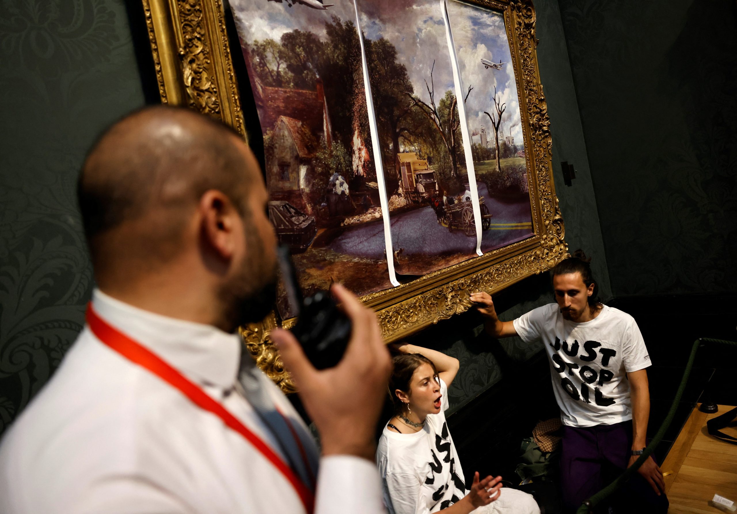 Activists from the 'Just Stop Oil' campaign group, with hands glued to the frame of the painting 'The Hay Wain' by English artist John Constable, but covered in a mock 'undated' version including roads and aircraft, protest against the use of fossil fuels, in the National Gallery in London on July 4, 2022. CARLOS JASSO/AFP via Getty Images