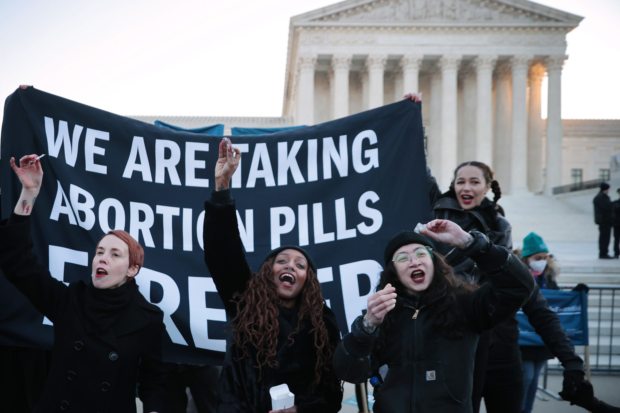 WASHINGTON, DC - DECEMBER 01: (L-R) Lila Bonow, Alana Edmondson and Aiyana Knauer prepare to take abortion pill while demonstrating in front of the U.S. Supreme Court as the justices hear hear arguments in Dobbs v. Jackson Women's Health, a case about a Mississippi law that bans most abortions after 15 weeks, on December 01, 2021 in Washington, DC. (Photo by Chip Somodevilla/Getty Images)