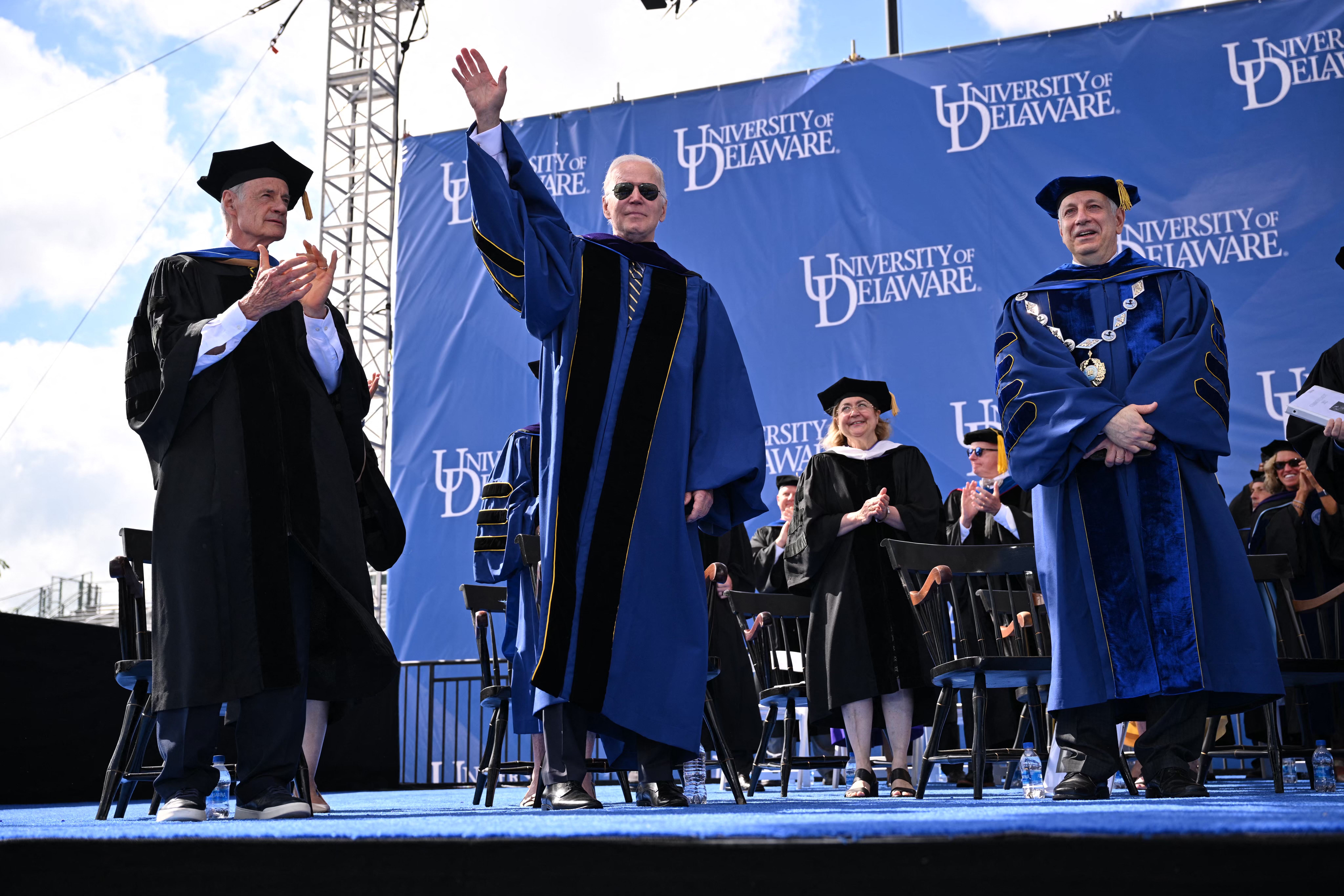 US President Joe Biden, with with University of Delaware President Dennis Assanis (R) and Senator Tom Carper (L), attends the graduation ceremony for his alma mater, the University of Delaware, at Delaware Stadium, where he will deliver the commencement address, in Newark, Delaware, on May 28, 2022. 