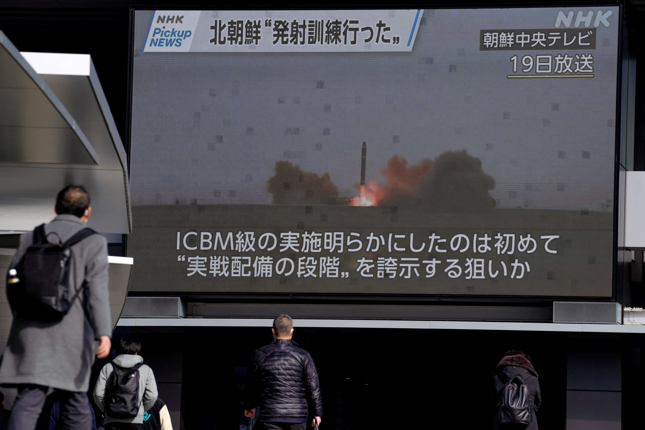 Pedestrians walk past a screen in Tokyo on February 20, 2023, displaying North Korea's missile launch footage broadcasted by Korean Central Television on February 19