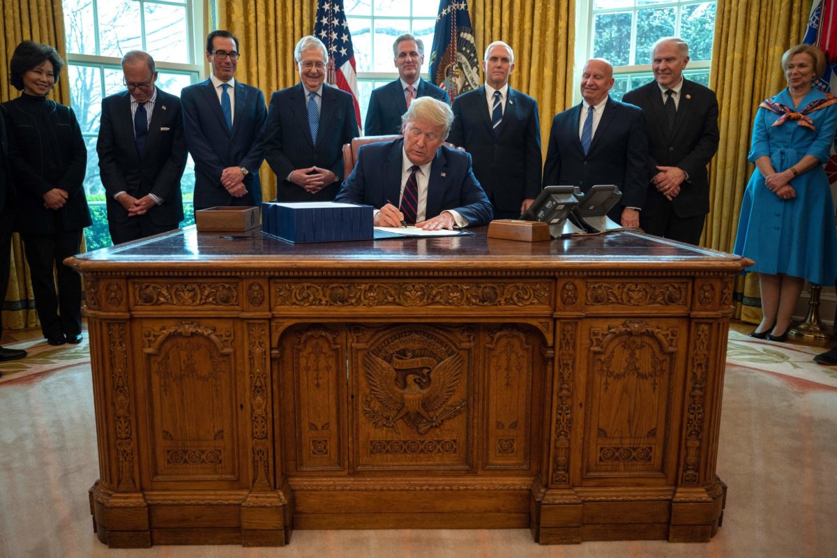 US President Donald Trump signs the CARES act, a $2 trillion rescue package to provide economic relief amid the coronavirus outbreak, at the Oval Office of the White House on March 27, 2020. - After clearing the Senate earlier this week, and as the United States became the new global epicenter of the pandemic with 92,000 confirmed cases of infection, Republicans and Democrats united to greenlight the nation's largest-ever economic relief plan. (Photo by JIM WATSON / AFP) (Photo by JIM WATSON/AFP via Getty Images)