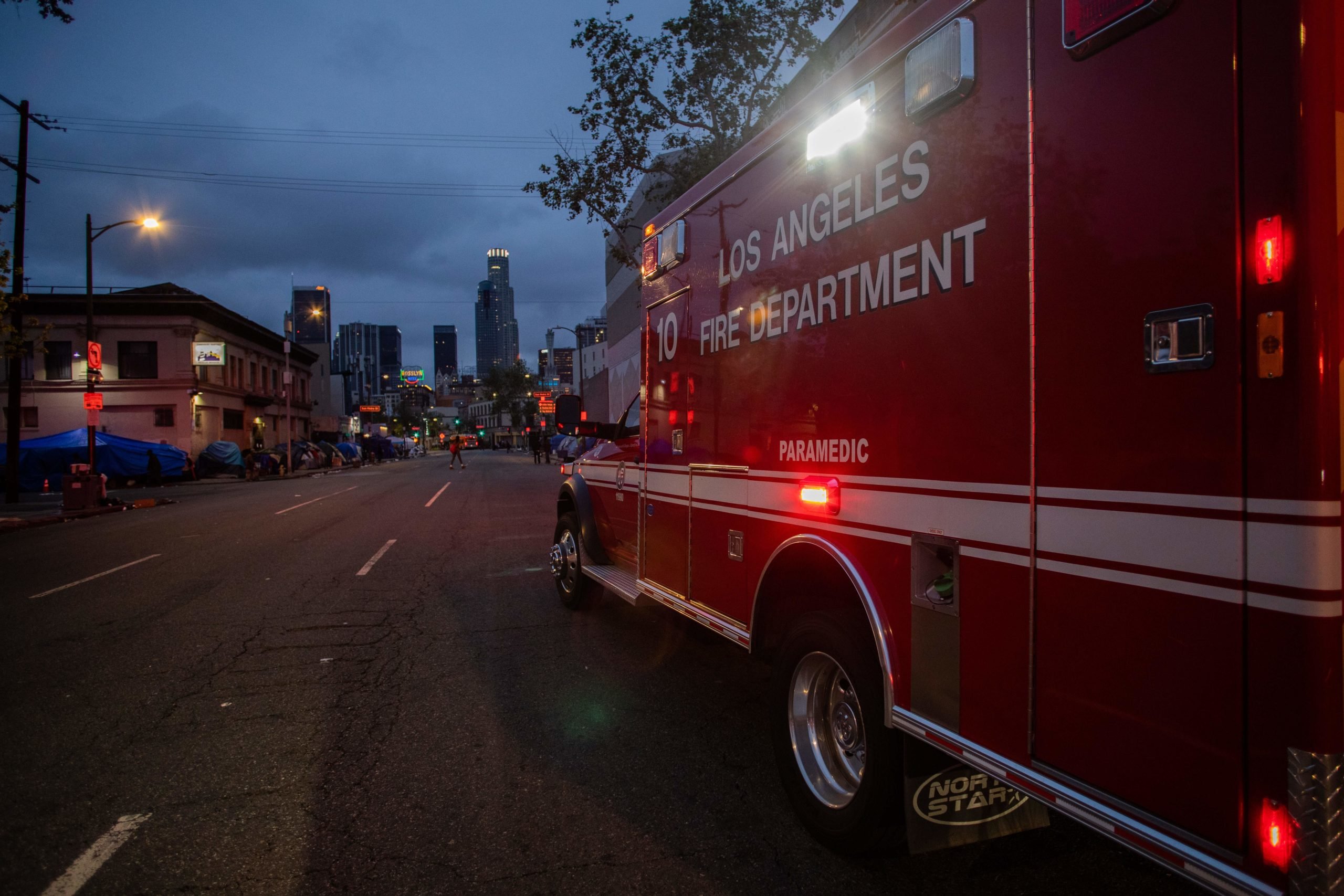 Een ambulance van LAFD Station No9 rijdt op 12 april 2020 langs Skid Row in het centrum van Los Angeles, Californië.  - LA Fire Station 9, een van de drukste brandweerkazernes van het land, bevindt zich in de frontlinie van de dakloosheidscrisis in Californië en de pandemie van het coronavirus.