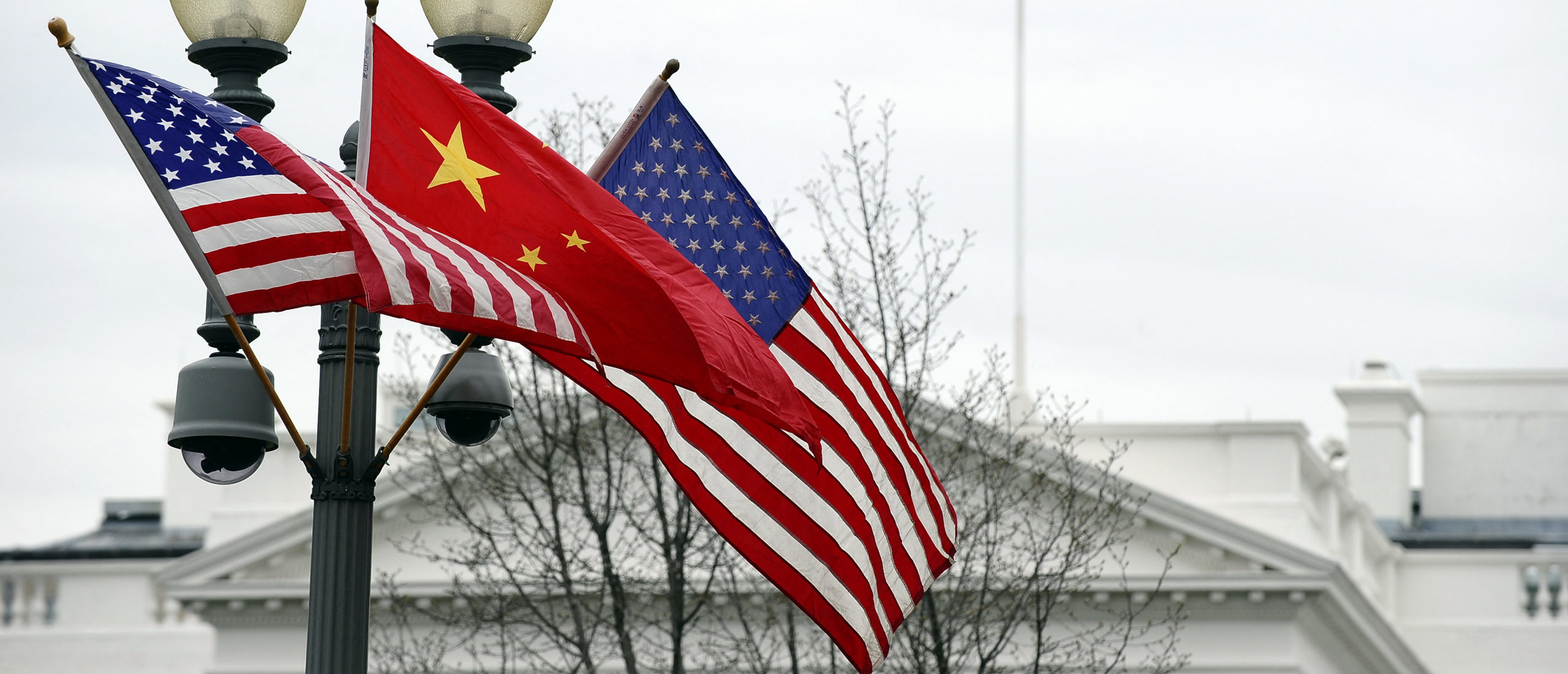 A lamp post is adorned with a Chinese national flag in between two US flags in front of the White House in Washington, DC, on January 17, 2011 previous to Chinese President Hu Jintao's state visit. Ahead of a legacy-building state visit to the US, Chinese President Hu Jintao called for "common ground" while acknowledging that "sensitive issues" needed to be addressed. AFP PHOTO/Jewel Samad (Photo by Jewel SAMAD / AFP) (Photo by JEWEL SAMAD/AFP via Getty Images)