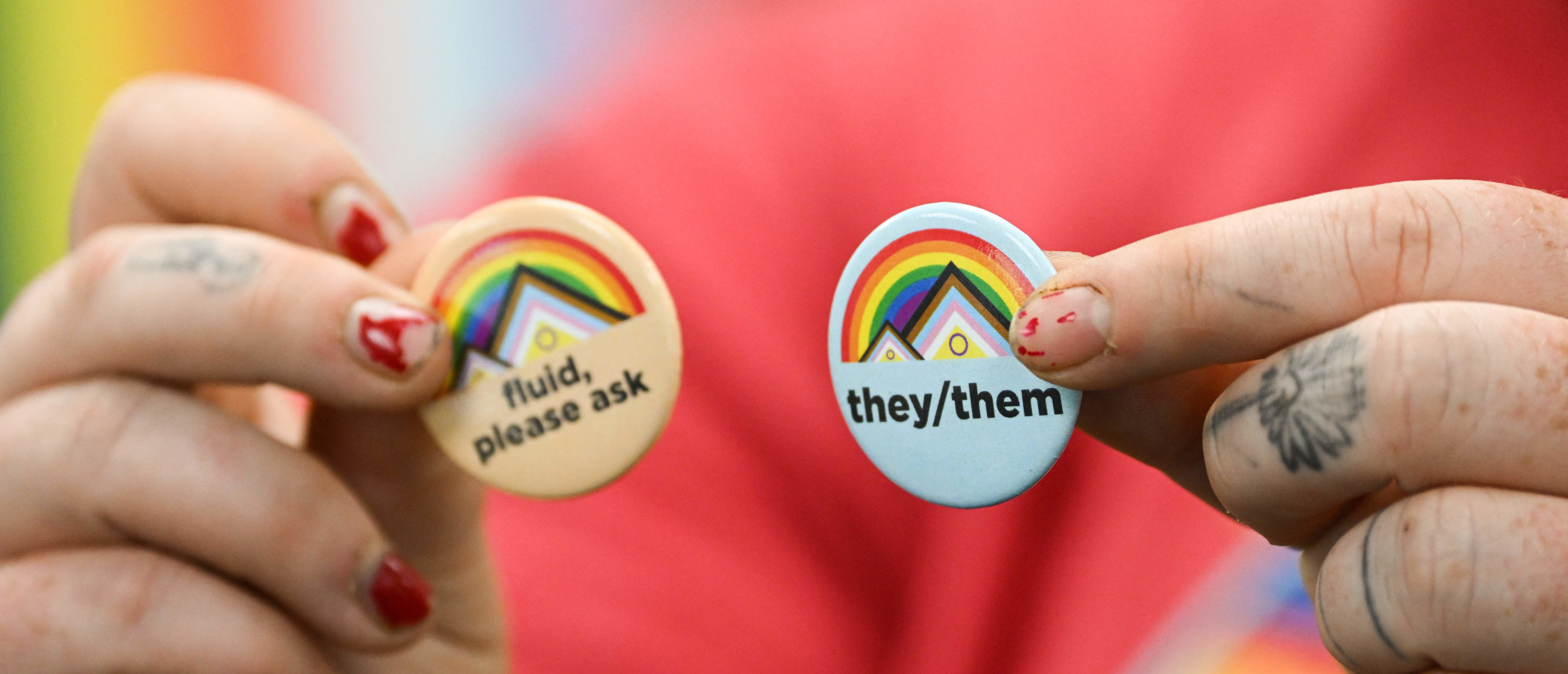 Laramie LGBTQ residen and University of Wyoming Alumni Ray Kasckow holds pins about gender pronouns, on the University of Wyoming campus in Laramie, Wyoming, on August 13, 2022.