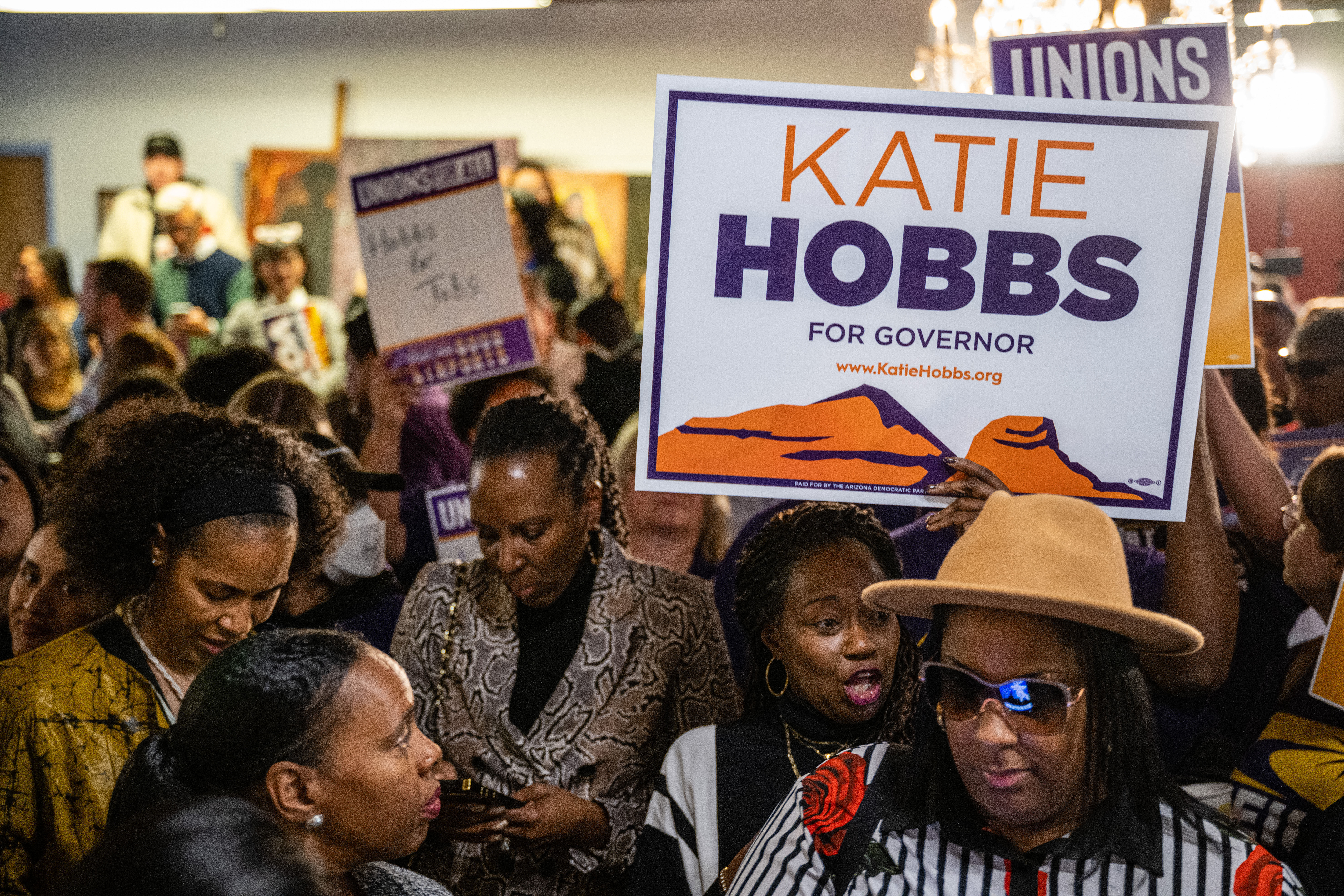 Attendees interact while holding signs supporting Governor-elect of Arizona Katie Hobbs at a rally to celebrate Hobbs' victory on November 15, 2022 in Phoenix, Arizona. Major news organizations announced her win over Trump endorsed republican candidate for governor Kari Lake. (Photo by Jon Cherry/Getty Images)