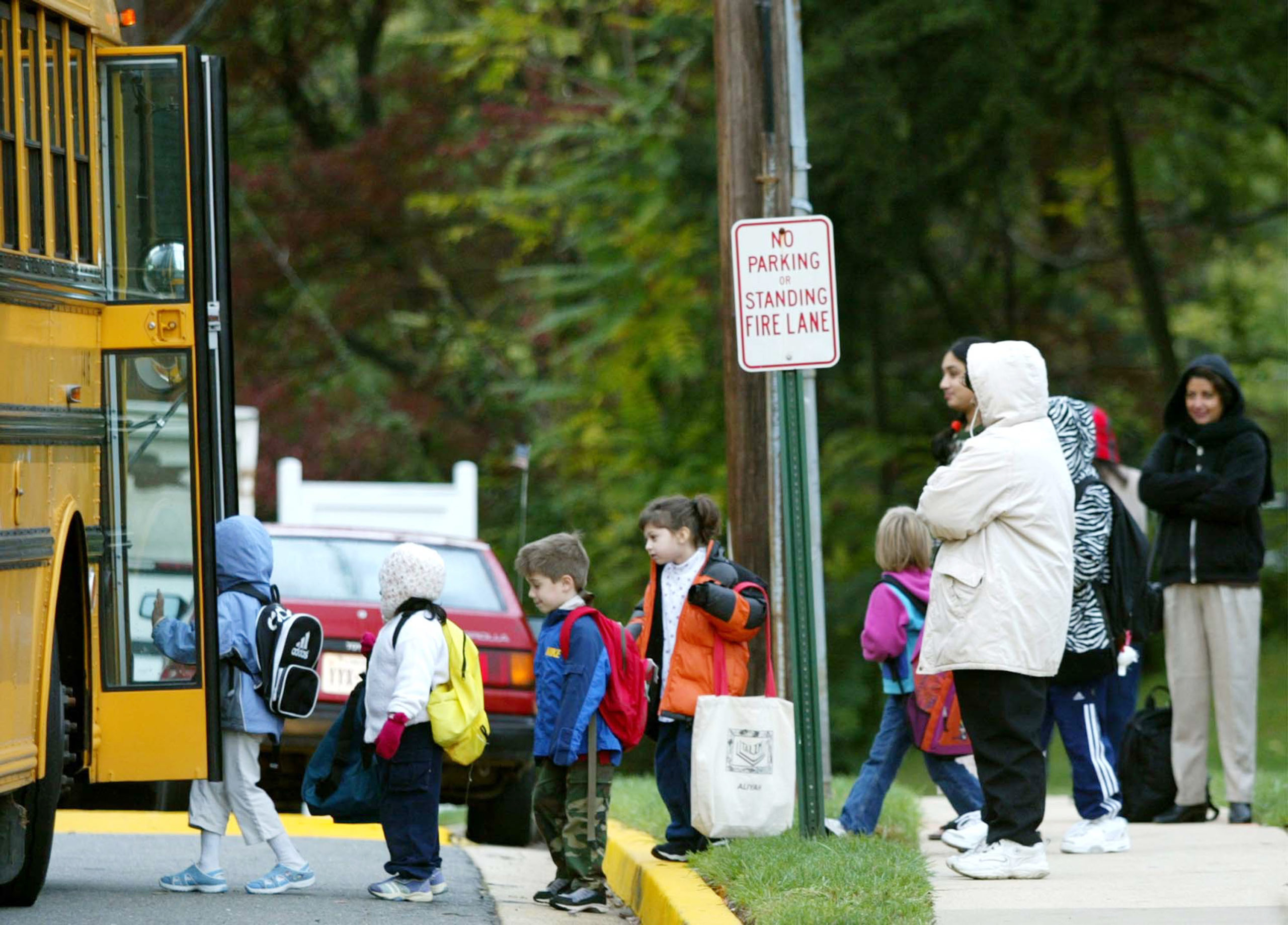 Parents watch as children step onto a Fairfax County school bus October 15, 2002, at Police headquarters in Falls Church, Virginia. Manger confirmed that the women who was shot and killed at the Home Depot store in Falls Church, Virginia was the work of the Beltway sniper. (Photo by Mark Wilson/Getty Images)