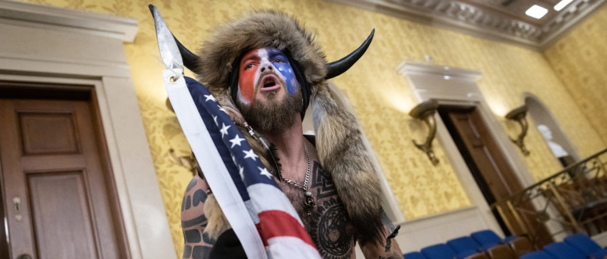 WASHINGTON, DC - JANUARY 06: Jacob Chansley, also known as the "QAnon Shaman," screams "Freedom" inside the U.S. Senate chamber after the U.S. Capitol was breached by a mob during a joint session of Congress on January 6, 2021 in Washington, DC. Congress held a joint session to ratify President-elect Joe Biden's 306-232 Electoral College win over President Donald Trump. Pro-Trump protesters illegally entered the U.S. Capitol building following rallies in the nation's capital. (Photo by Win McNamee/Getty Images)