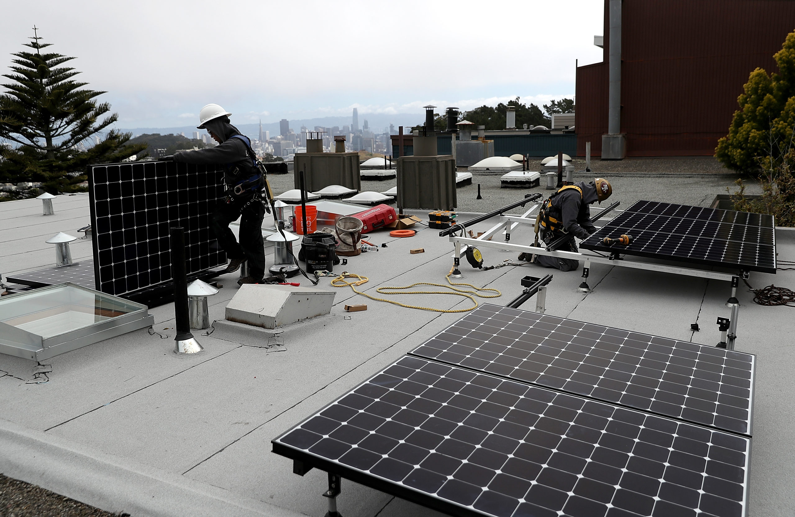 SAN FRANCISCO, CA - MAY 09: Luminalt solar installers Pam Quan (L) and Walter Morales (R) install solar panels on the roof of a home on May 9, 2018 in San Francisco, California. The California Energy Commission is set to vote on proposed legislation that would require all new homes in the state of California to have solor panels. If passed, the new mandate would require the panels on new homes up to three stories tall and is estimated to cost nearly $10K per home. (Photo by Justin Sullivan/Getty Images)