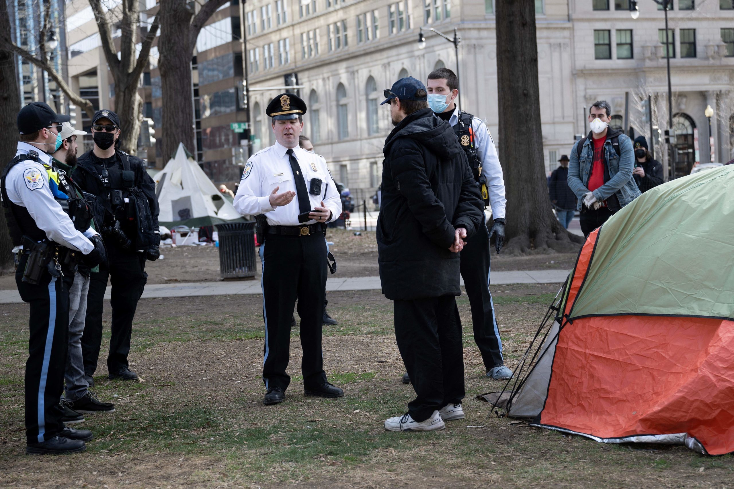 Park Police argue with a man who did not want to leave as members of the US National Park Service clear a homeless encampment from McPherson Square, two blocks from the White House, on February 15, 2023 in Washington, DC. - Some 56 people live in the federal park, which is being cleared ahead of the initial April schedule due to safety concerns. (Photo by Brendan Smialowski / AFP) (Photo by BRENDAN SMIALOWSKI/AFP via Getty Images)