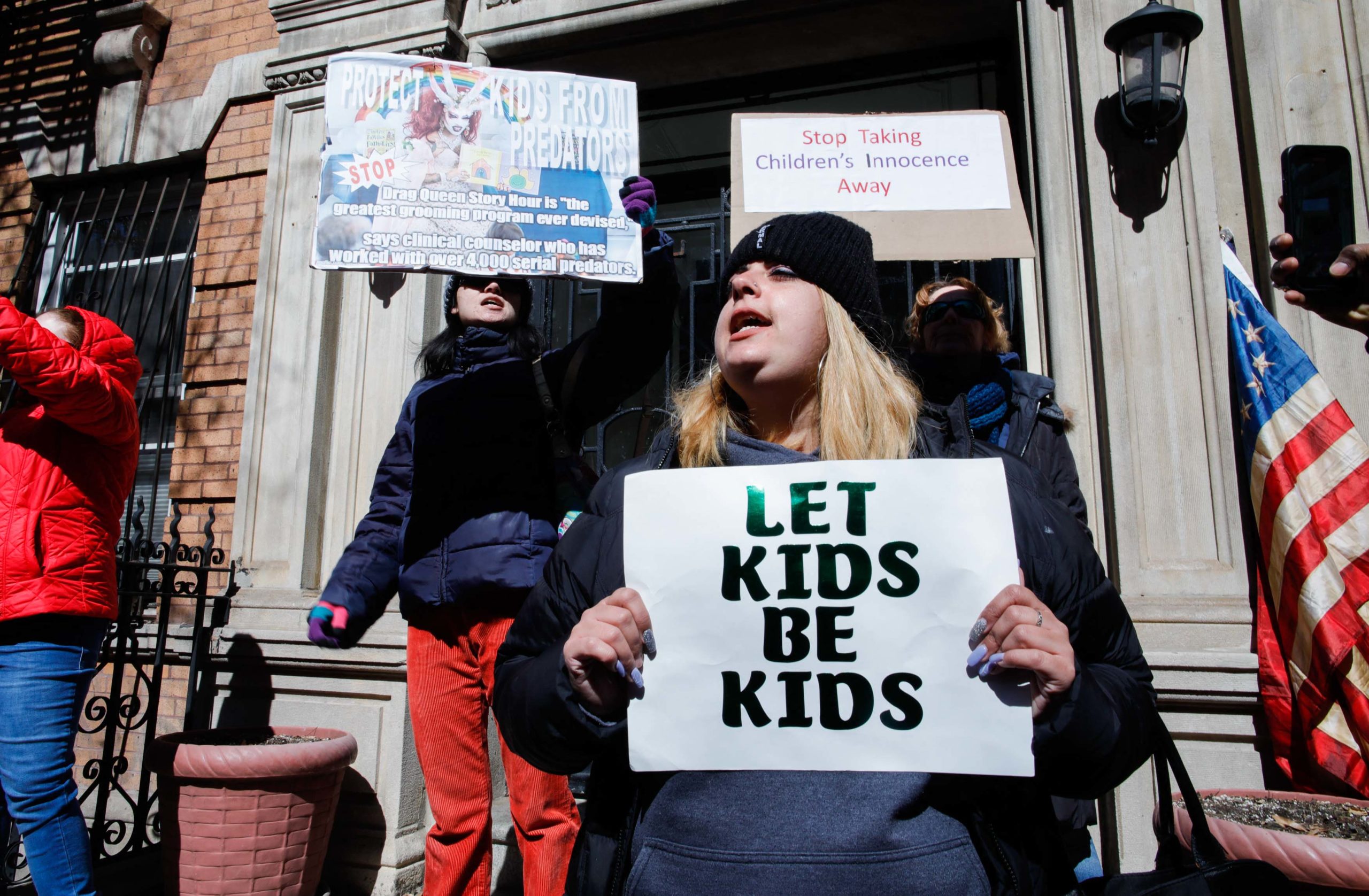 A woman holds a sign reading "Let Kids Be Kids" as she protests across supporters of Drag Story Hour outside the LGBTQ center in New York City on March 19, 2023. (Photo by KENA BETANCUR / AFP) (Photo by KENA BETANCUR/AFP via Getty Images)