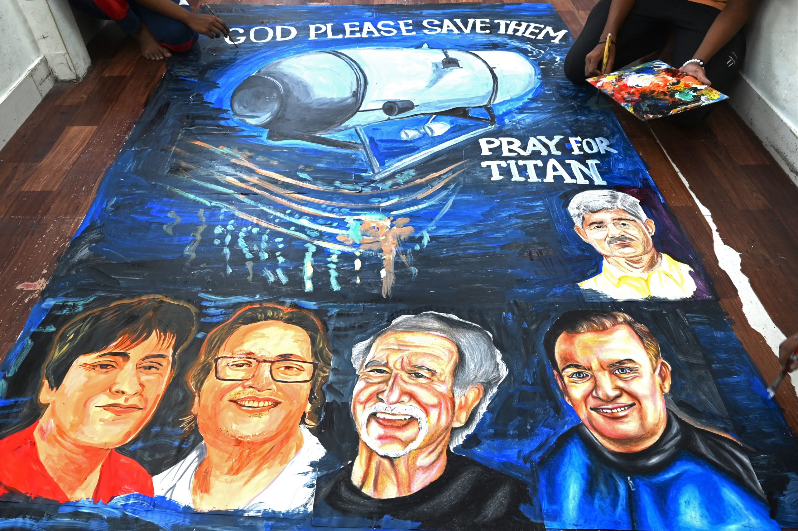 TOPSHOT - Art school students give final touches to a painting depicting five people aboard a submersible named Titan, that went missing near the wreck of the Titanic, in Mumbai on June 22, 2023. (Photo by INDRANIL MUKHERJEE / AFP) (Photo by INDRANIL MUKHERJEE/AFP via Getty Images)