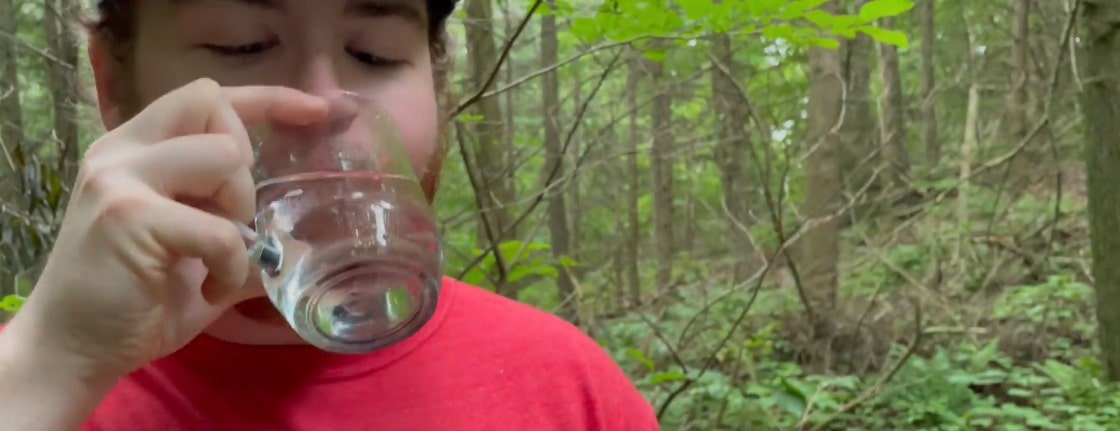 Daily Caller reporter Dylan Housman drinks water straight from the ground at the Sandy Hook water spring. (Daily Caller)
