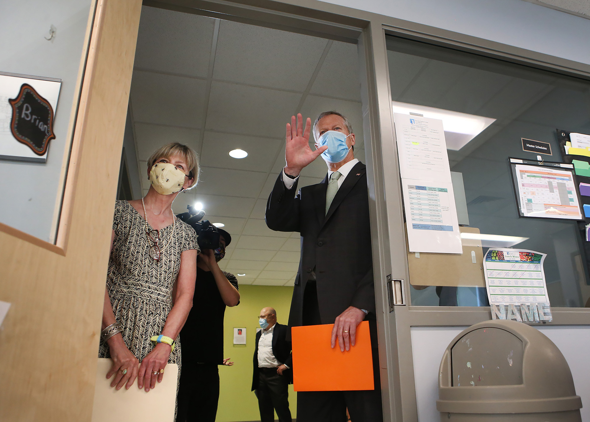 Governor Charlie Baker and Secretary of Health and Human Services Marylou Sudders wave to students through a classroom door as they tour The New England Center for Children on July 13, 2020 in Southborough, Massachusetts. (Photo by Nancy Lane / POOL / AFP) (Photo by NANCY LANE/POOL/AFP via Getty Images)