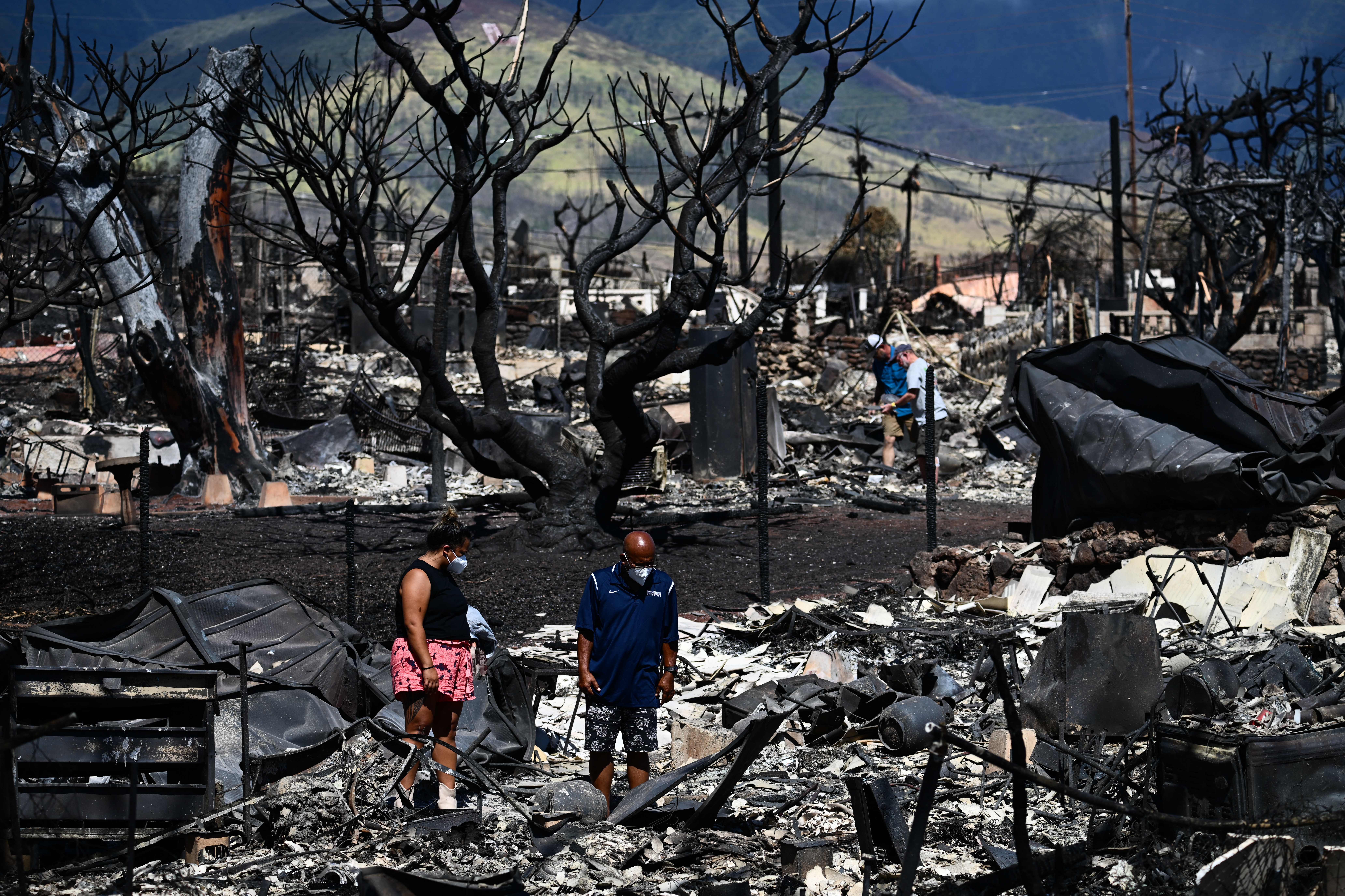 Taylor Ganer and Hano Ganer search for their belongings in the ashes of their family's burnt-down house in the aftermath of a wildfire in Lahaina, western Maui, Hawaii on August 11, 2023. A wildfire that left Lahaina in charred ruins has killed at least 67 people, authorities said on August 11, making it one of the deadliest disasters in the US state's history. Brushfires on Maui, fueled by high winds from Hurricane Dora passing to the south of Hawaii, broke out August 8 and rapidly engulfed Lahaina. (Photo by Patrick T. Fallon / AFP) (Photo by PATRICK T. FALLON/AFP via Getty Images)
