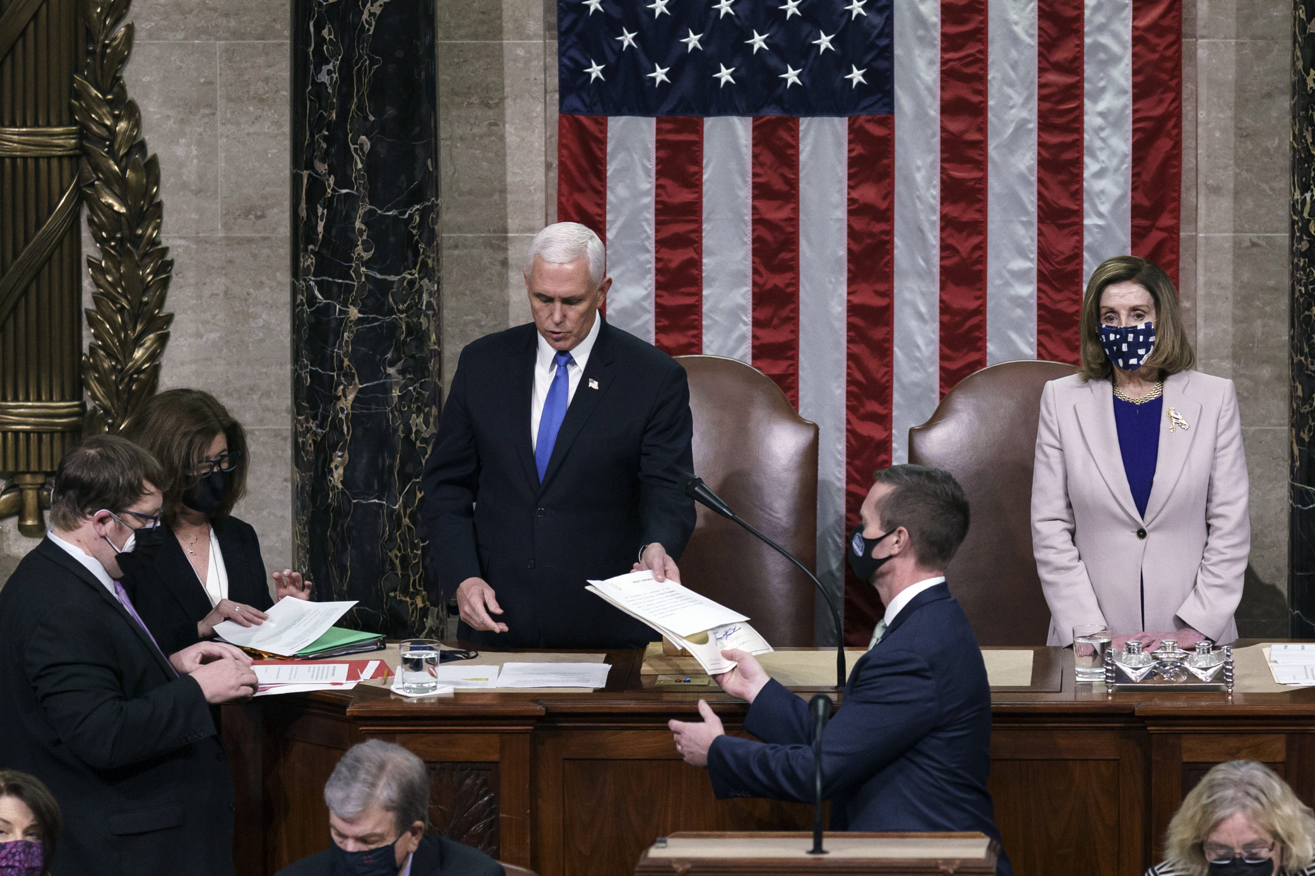 WASHINGTON, DC - JANUARY 07: Vice President Mike Pence hands the West Virginia certification to staff as Speaker of the House Nancy Pelosi, D-Calif., listen during a joint session of Congress after working through the night, at the Capitol. (J. Scott Applewhite - Pool/Getty Images)
