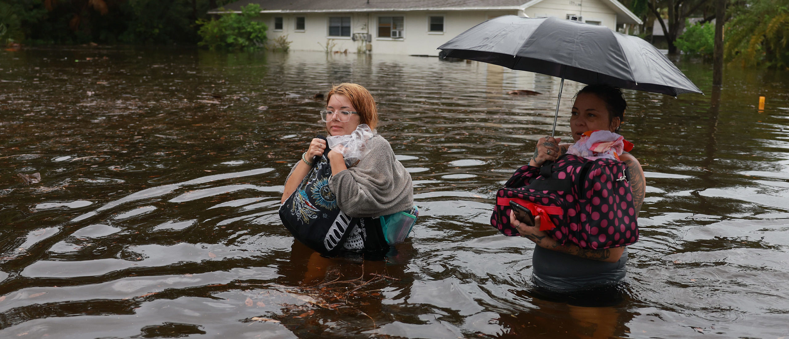 TARPON SPRINGS, FLORIDA - AUGUST 30: Makatla Ritchter (L) and her mother, Keiphra Line wade through flood waters after having to evacuate their home when the flood waters from Hurricane Idalia inundated it on August 30, 2023 in Tarpon Springs, Florida. Hurricane Idalia is hitting the Big Bend area of Florida. (Photo by Joe Raedle/Getty Images)