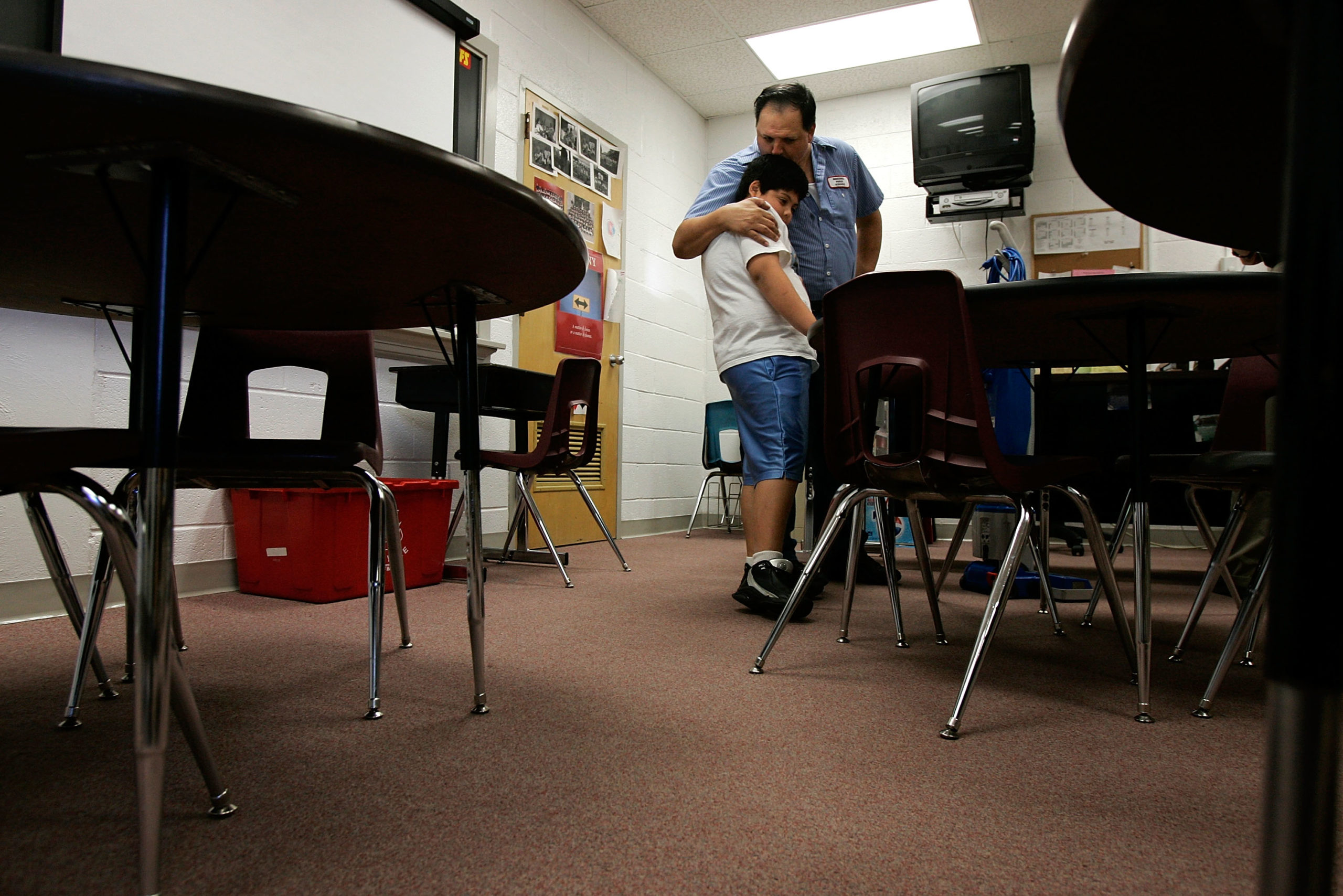 Custodian Francisco ?Paco? Inzunza (R) hugs his younger son Anthony (L), who is a fifth grader at the same school, in a classroom at Bueker Middle School September 27, 2005 in Marshall, Missouri. Paco illegally came to the United States to pursue his American dream from Mexico in 1991. After he and his family had settled in Marshall, he learned English for 3 years and started helping members of the local Latino community to translate for their daily lives. He was forced to admit his illegal statues when he was involved in a murder case as a translator and a witness. Paco is very well received by the people in his town because of his involvement in helping others. He also works very hard to support his own family. Many of his supporters had testified for him at his deportation hearing and tried to lobby for a law change before the next time he has to go back to court on February 13, 2007, so Paco can stay in the United States permanently. (Photo by Alex Wong/Getty Images)