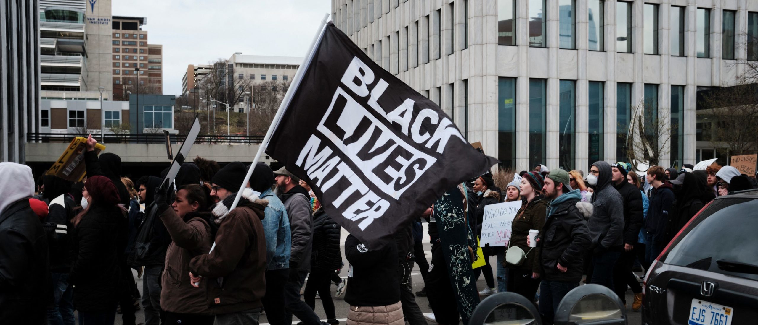 Protesters hold a Black Lives Matter flag as they march for Patrick Lyoya, a Black man who was fatally shot by a police officer, in downtown Grand Rapids, Michigan, April 16, 2022. - One of four videos from the April 4 incident shows the officer lying on the back of 26-year-old Black man Patrick Lyoya as the two scuffled after a traffic stop and then appearing to shoot him in the head. (Photo by MUSTAFA HUSSAIN and Mustafa Hussain / AFP) (