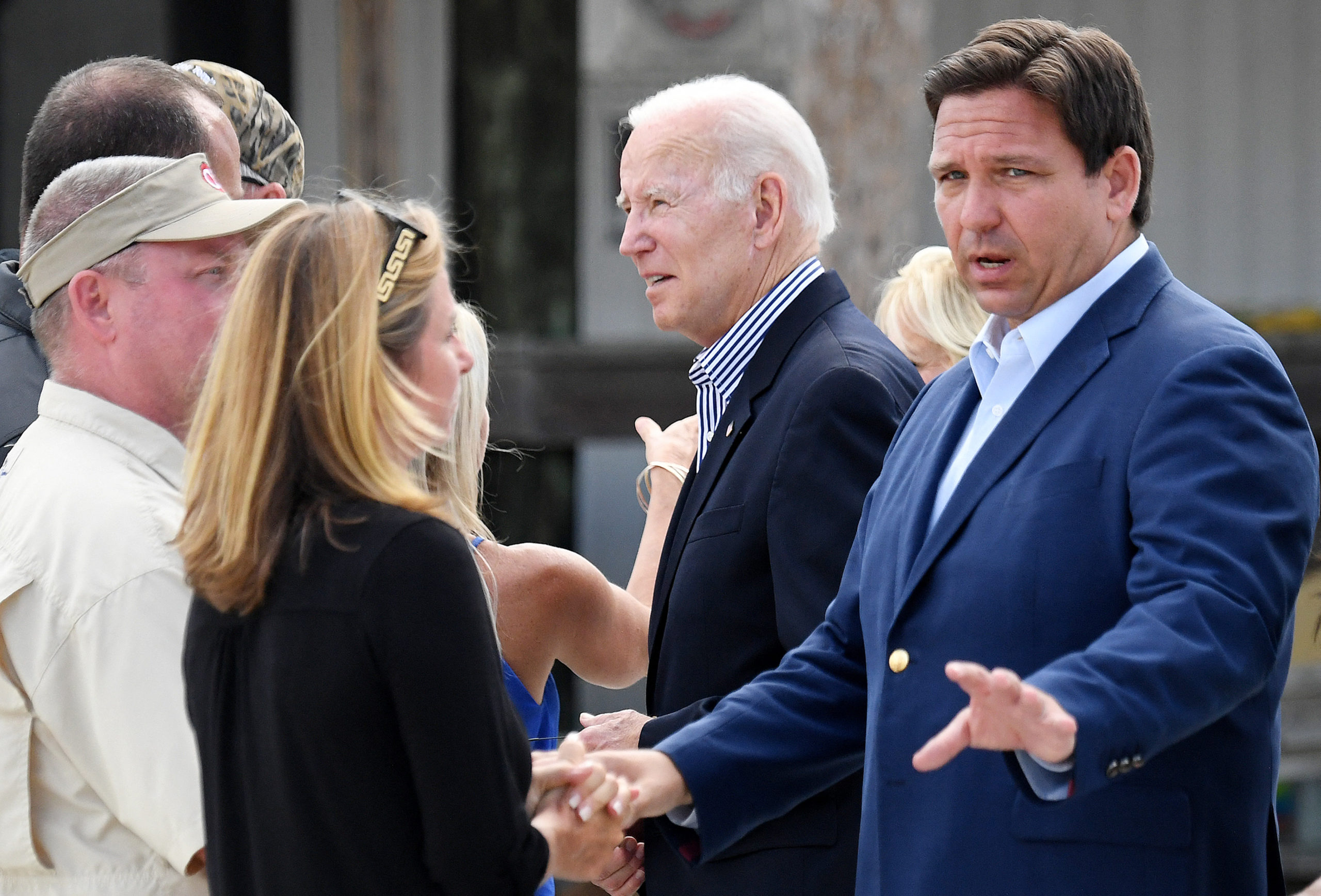 Florida Governor Ron DeSantis (R) and US President Joe Biden (C) speak with local residents impacted by Hurricane Ian at Fishermans Pass in Fort Myers, Florida, on October 5, 2022. (Photo by OLIVIER DOULIERY / AFP) (Photo by OLIVIER DOULIERY/AFP via Getty Images)