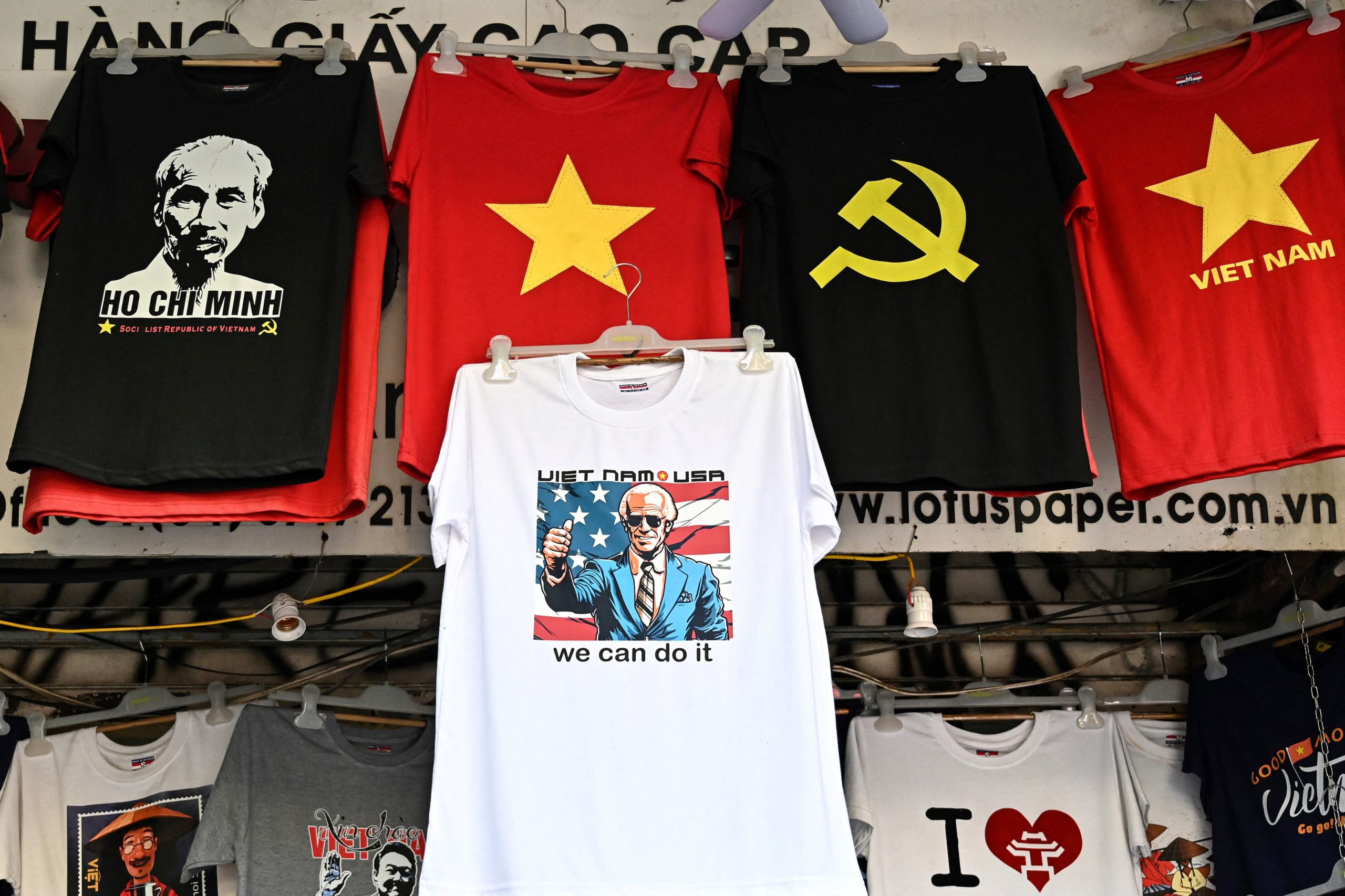 An employee installs a t-shirt with an image of photo of US President Joe Biden (C) next to t-shirts showing communist symbols and a portrait Vietnamese late President Ho Chi Minh (L) in a souvenir shop in Hanoi on September 6, 2023, ahead of US President's visit to Hanoi on September 10. (Photo by Nhac NGUYEN / AFP) (Photo by NHAC NGUYEN/AFP via Getty Images)