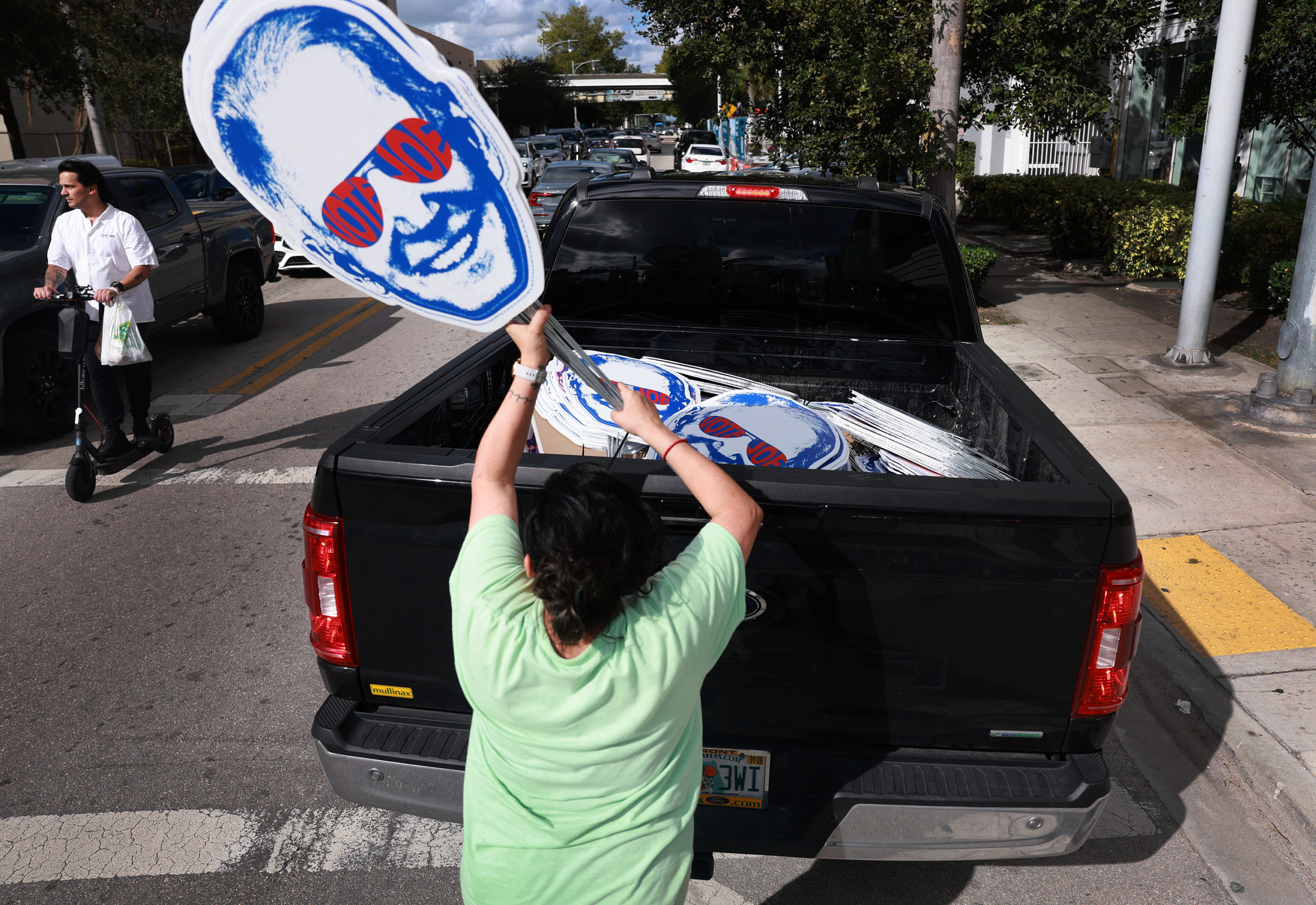 Vanessa Brito works on placing campaign signs supporting President Joe Biden into the back of a pickup truck before the third Republican Presidential Primary Debate at the Adrienne Arsht Center for the Performing Arts of Miami-Dade County on November 08, 2023 in Miami, Florida. The debate featuring five Republican Presidential candidates is scheduled to be aired on NBC at 8 p.m. (Photo by Joe Raedle/Getty Images)