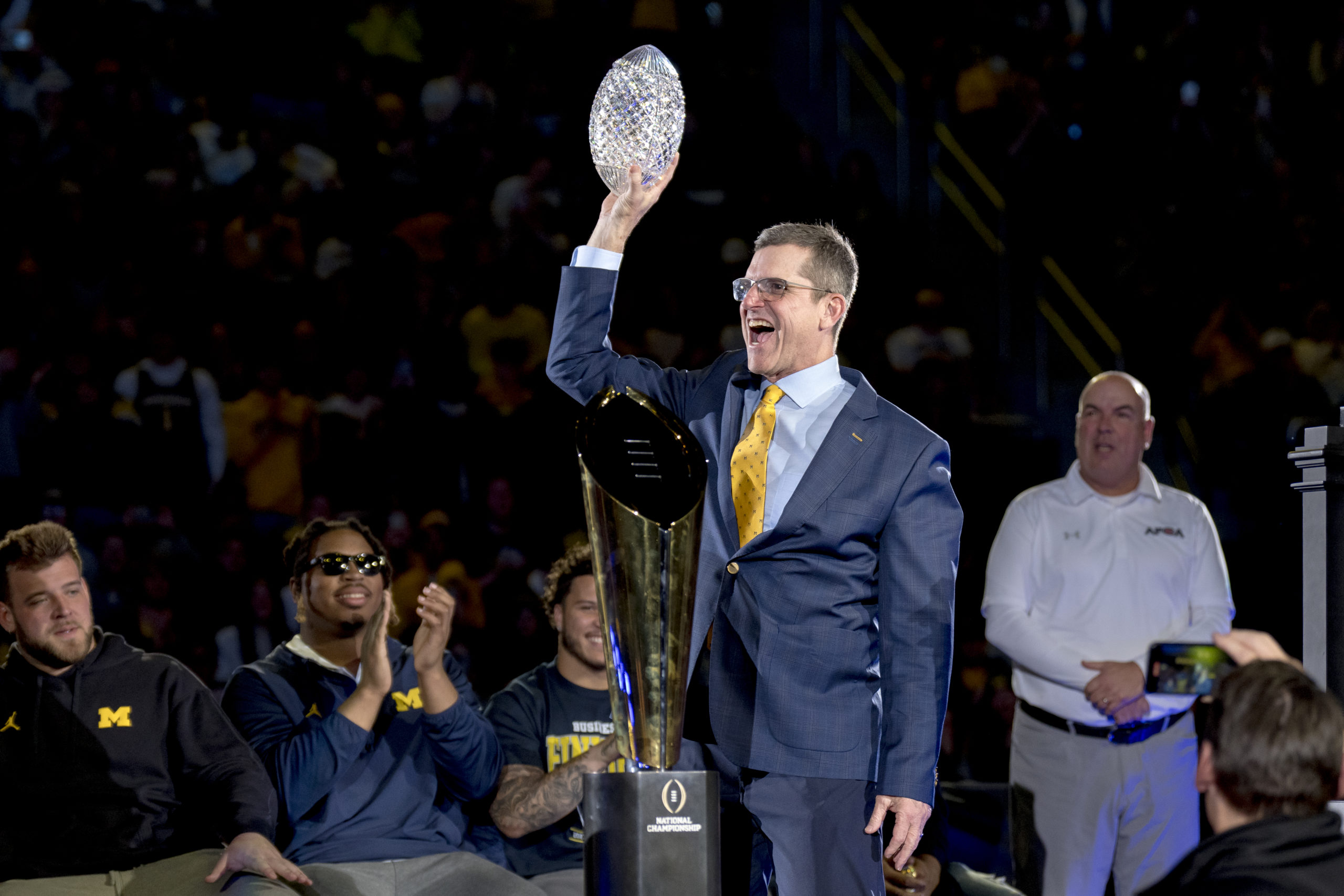ANN ARBOR, MICHIGAN - JANUARY 13: Head coach Jim Harbaugh of the Michigan Wolverines celebrates with the Coaches' Trophy during the Michigan Wolverines football National Championship celebration on January 13, 2024 at Crisler Center in Ann Arbor, Michigan. Nic Antaya/Getty Images