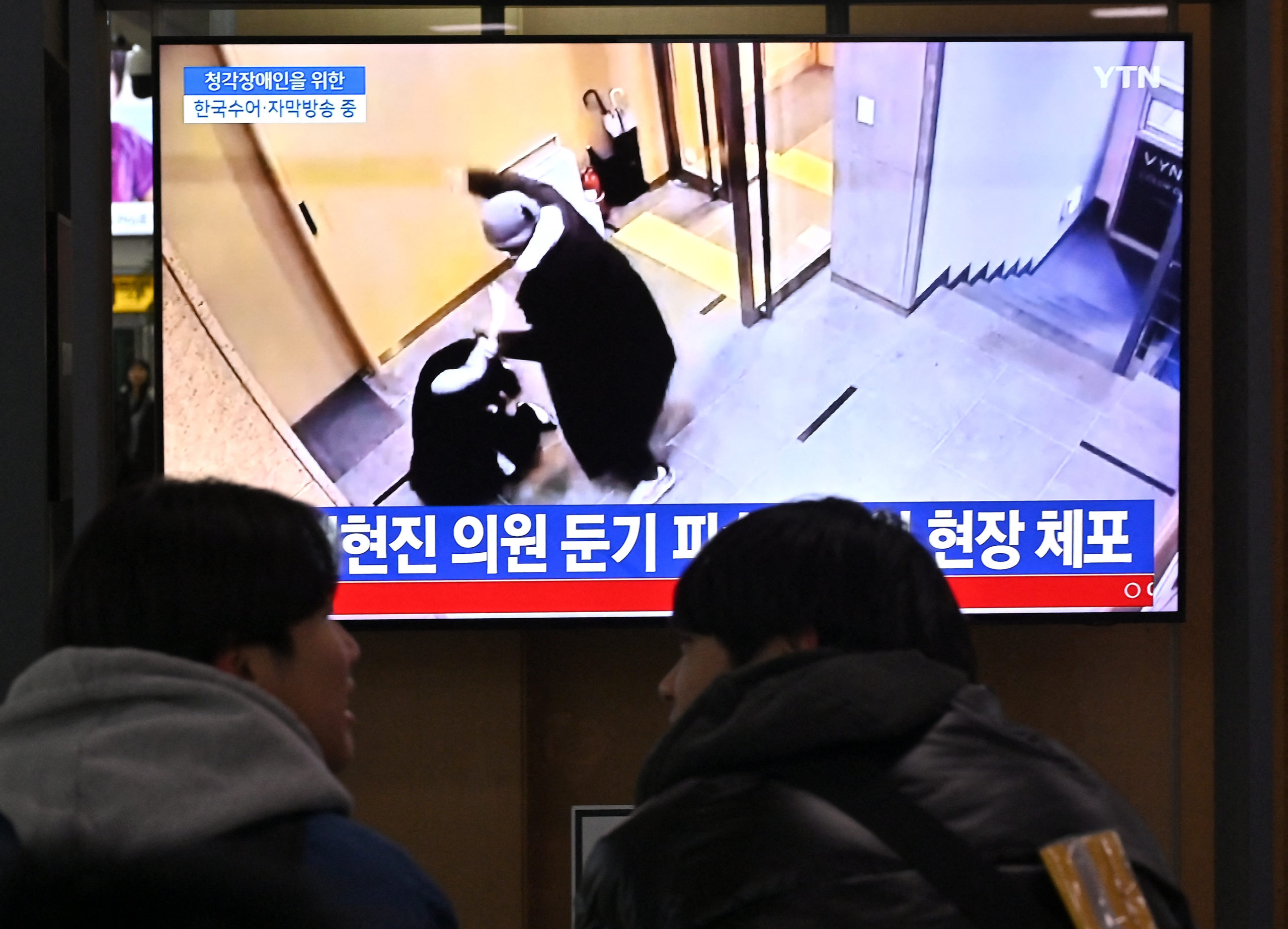 People watch a television screen showing a news broadcast with a closed-circuit television footage of the scene where South Korean ruling People Power Party's lawmaker Bae Hyun-jin being assaulted in Gangnam district, at a railway station in Seoul on January 25, 2024. (Photo by JUNG YEON-JE/AFP via Getty Images)