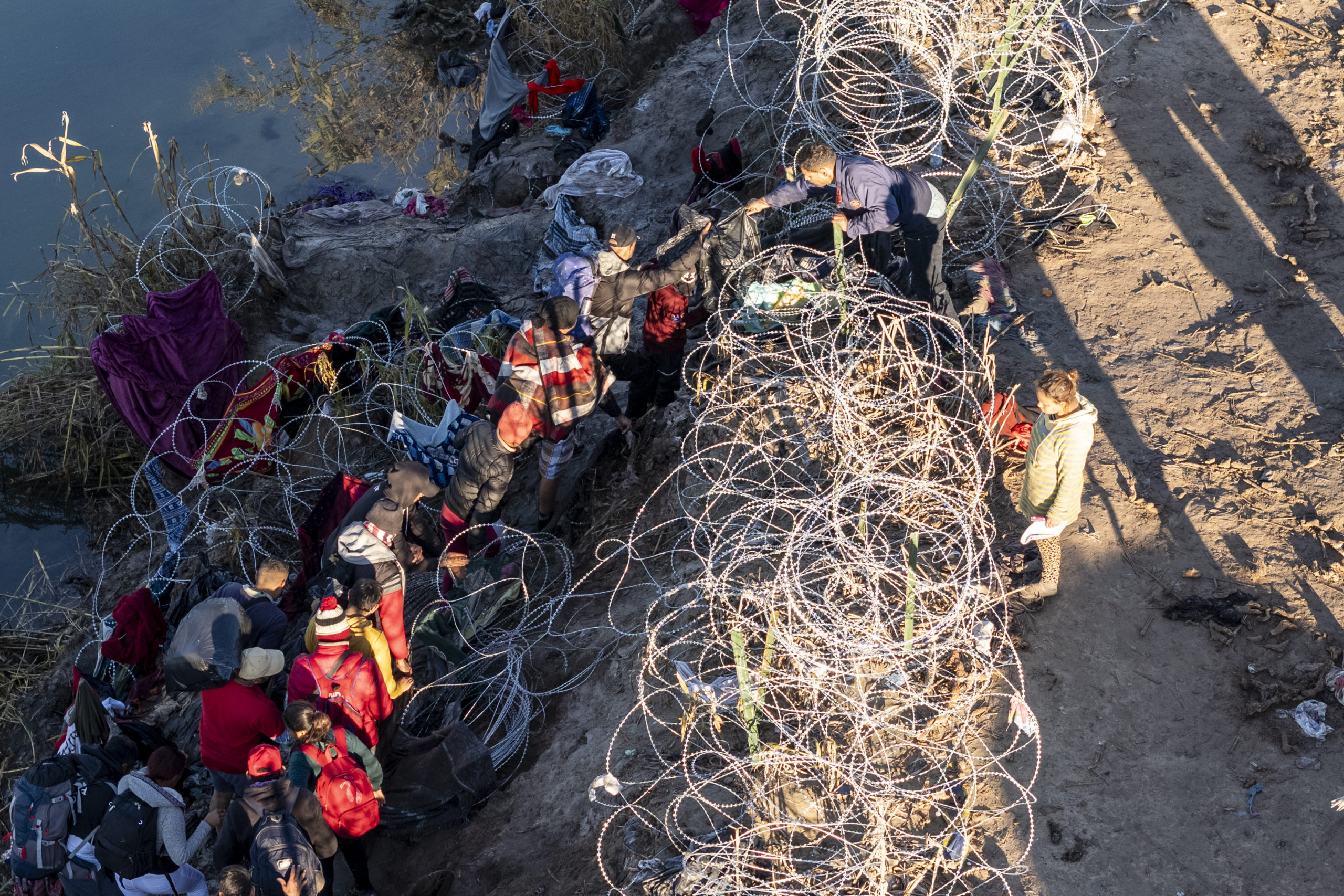 EAGLE PASS, TEXAS - DECEMBER 18: As seen from an aerial view immigrants climb through razor wire after crossing the Rio Grande from Mexico on December 18, 2023 in Eagle Pass, Texas. A surge as many as 12,000 immigrants per day crossing the U.S. southern border has overwhelmed U.S. immigration authorities in recent weeks. (Photo by John Moore/Getty Images)