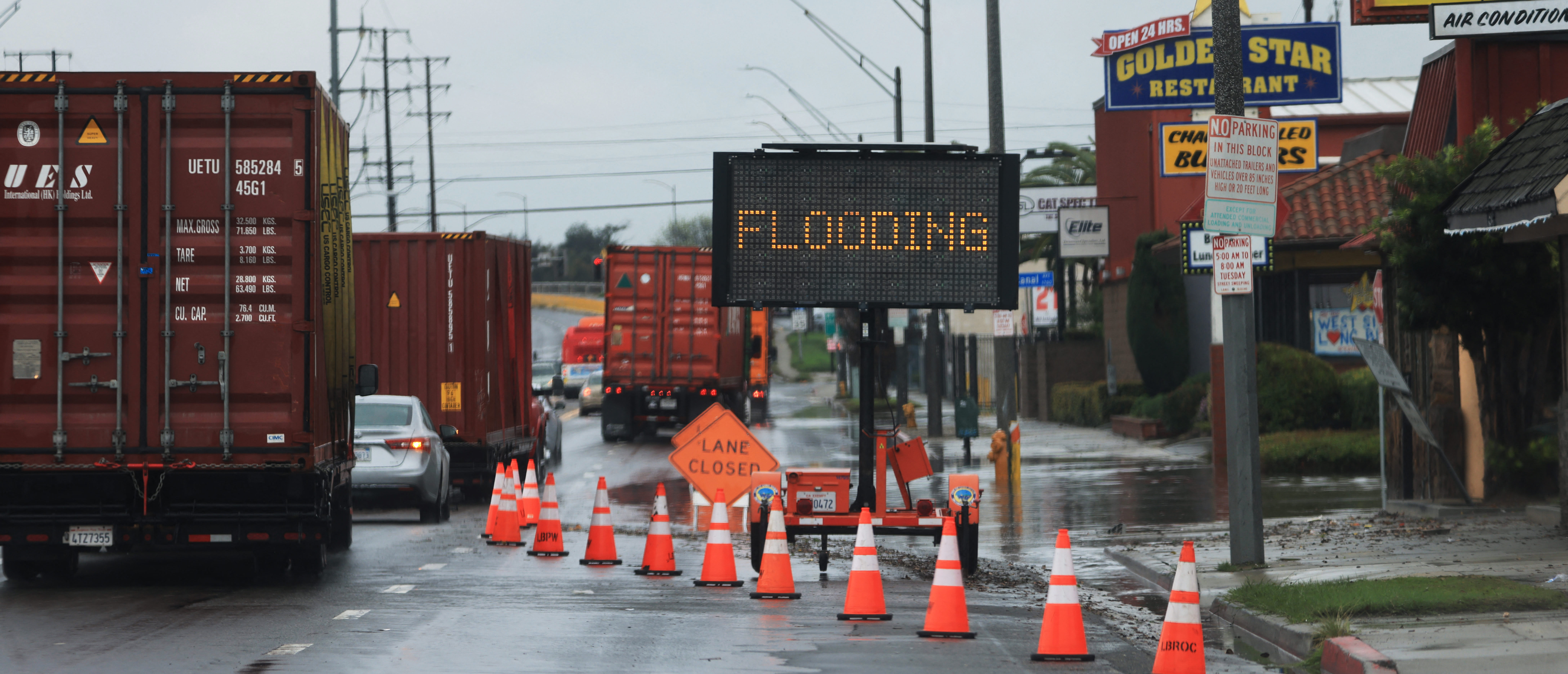 Flooding signs are placed by a road during a rain storm in Long Beach, California, on February 1, 2024. The US West Coast was getting drenched February 1, 2024 as the first of two powerful storms moved in, part of a "Pineapple Express" weather pattern that was washing out roads and sparking flood warnings. (Photo by David SWANSON / AFP) (