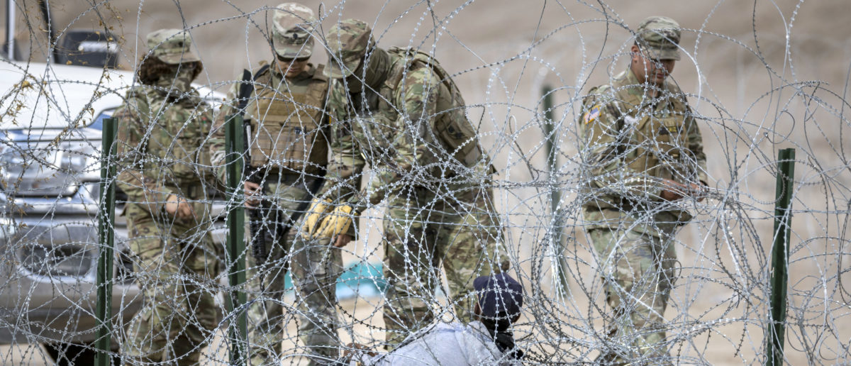 CIUDAD JUAREZ, MEXICO - JANUARY 31: Texas National Guard troops try to untangle an immigrant caught in razor wire after he crossed the U.S.-Mexico border into El Paso, Texas on January 31, 2024 from Ciudad Juarez, Mexico. Those who managed to get through the wire were then allowed to proceed further processing by U.S. Border Patrol agents. (Photo by John Moore/Getty Images)