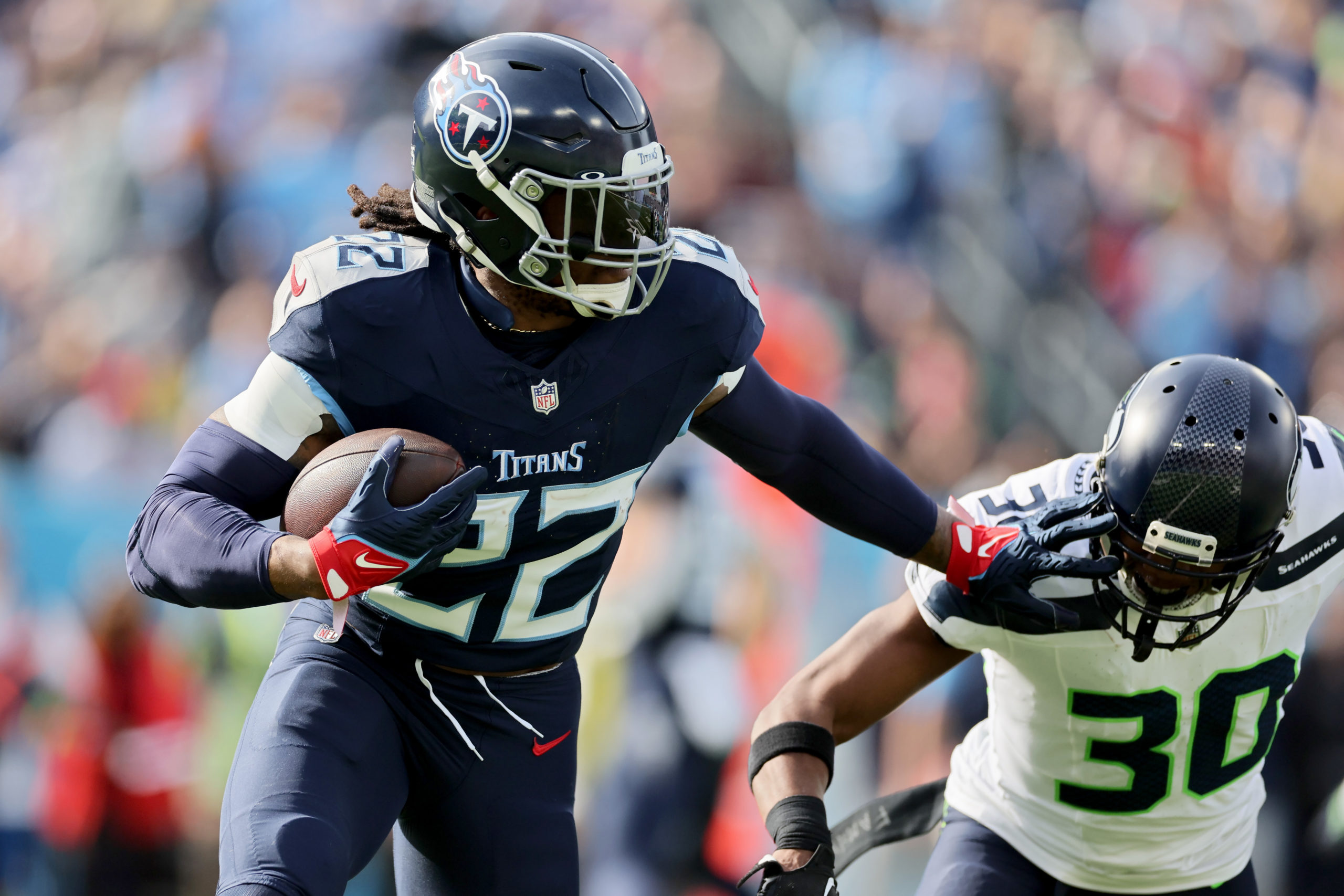 NASHVILLE, TENNESSEE - DECEMBER 24: Derrick Henry #22 of the Tennessee Titans stiff arms Michael Jackson #30 of the Seattle Seahawks during the first quarter at Nissan Stadium on December 24, 2023 in Nashville, Tennessee. Andy Lyons/Getty Images