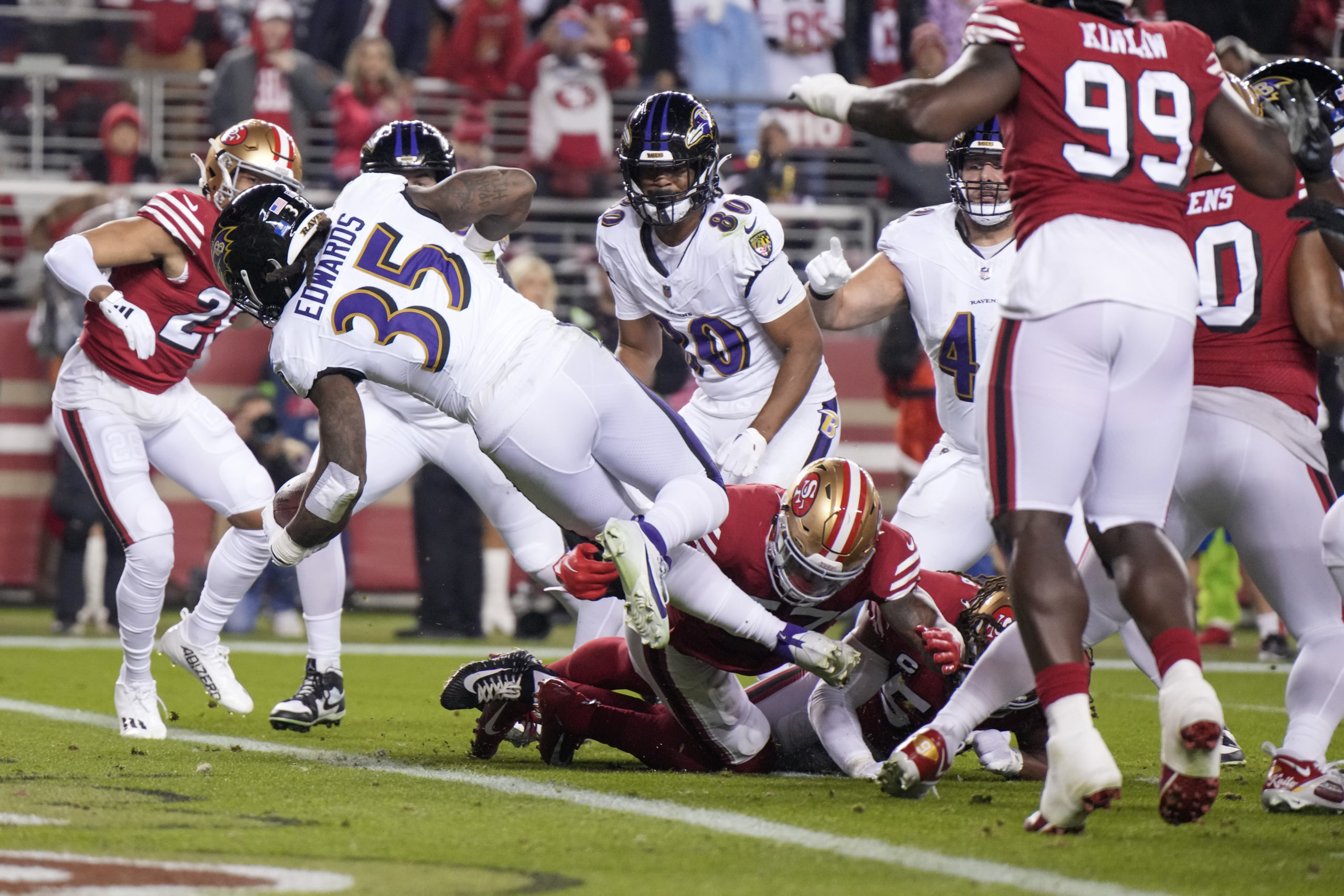 SANTA CLARA, CALIFORNIA - DECEMBER 25: Gus Edwards #35 of the Baltimore Ravens dives past Dre Greenlaw #57 of the San Francisco 49ers while scoring a rushing touchdown during the second quarter at Levi's Stadium on December 25, 2023 in Santa Clara, California. Loren Elliott/Getty Images