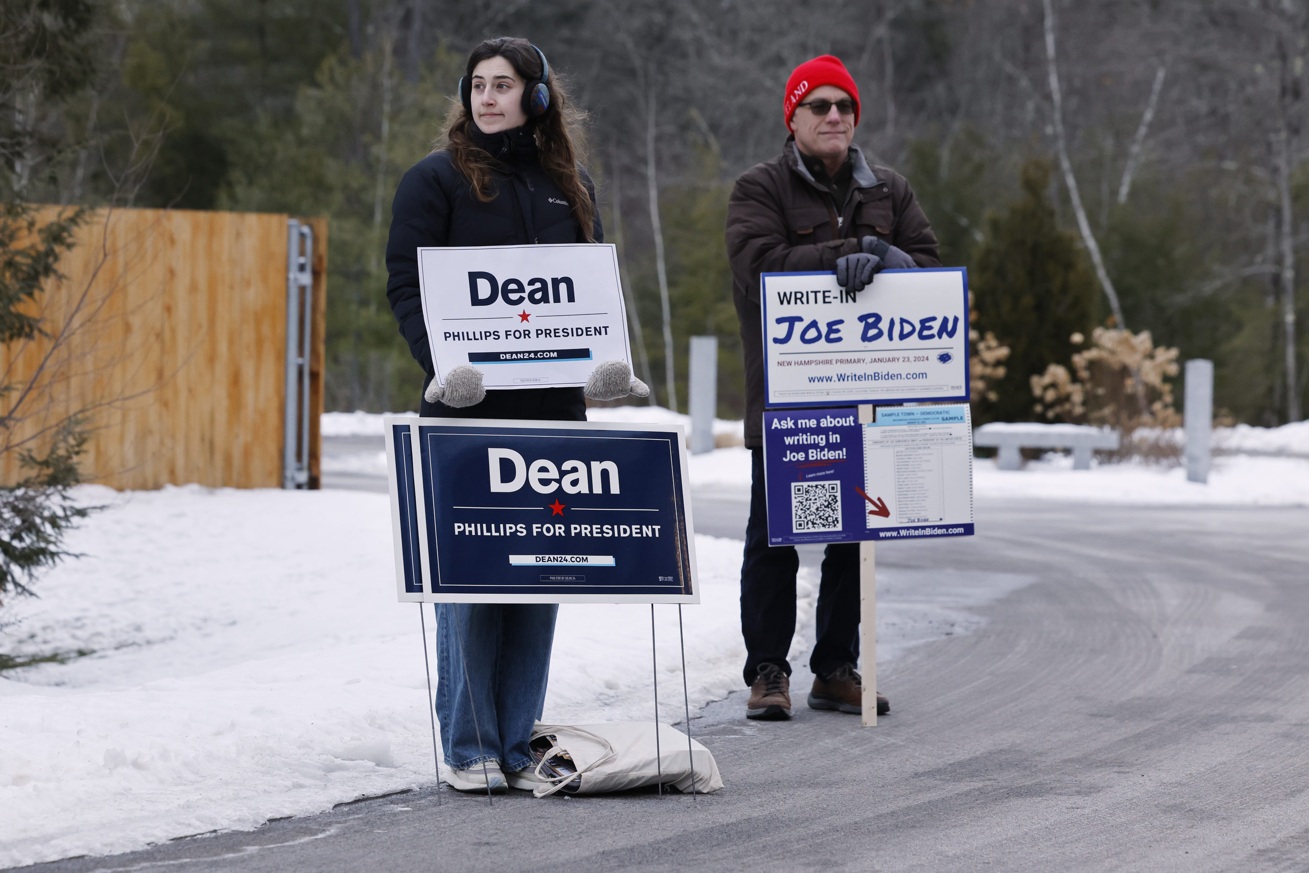 CONCORD, NEW HAMPSHIRE - JANUARY 23: Mae Hougo (L), a volunteer for U.S. Rep. Dean Phillips (D-MN), and Chuck Willing, a volunteer with the President Joe Biden write-in campaign, stand outside the polling place at The Barn at Bull Meadow during the New Hampshire presidential primary on January 23, 2024 in Concord, New Hampshire. With Florida Governor Ron DeSantis dropping out of the race two days earlier, Republican presidential candidates former President Donald Trump and former UN Ambassador and former South Carolina Governor Nikki Haley are battling it out in this first-in-the-nation primary. (Photo by Chip Somodevilla/Getty Images)