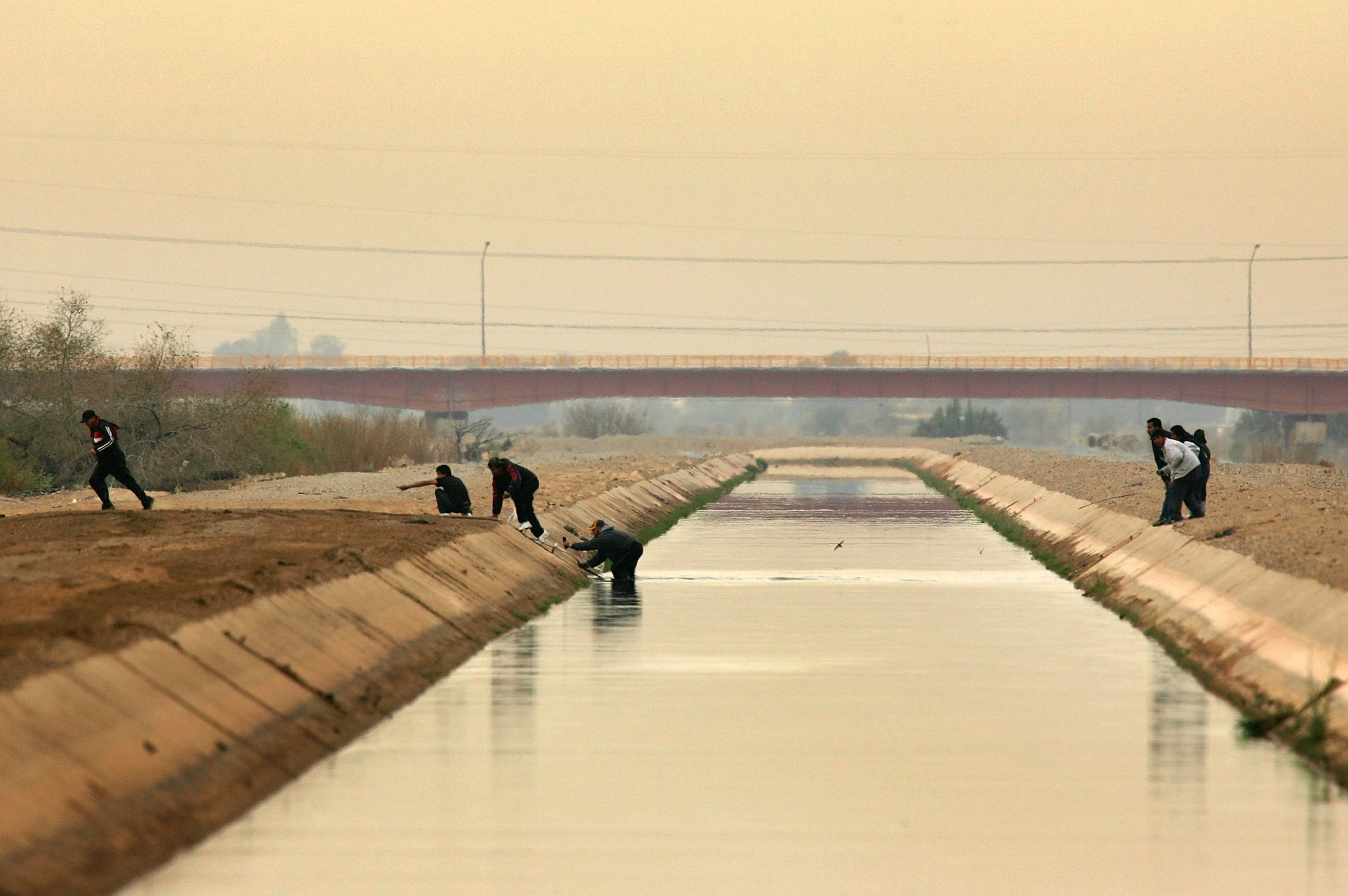  People cross a canal after walking over the dry Colorado River to cross illegally into the U.S. from Mexico on March 16, 2006 the border town of near San Luis, south of Yuma, Arizona. (Photo by David McNew/Getty Images)