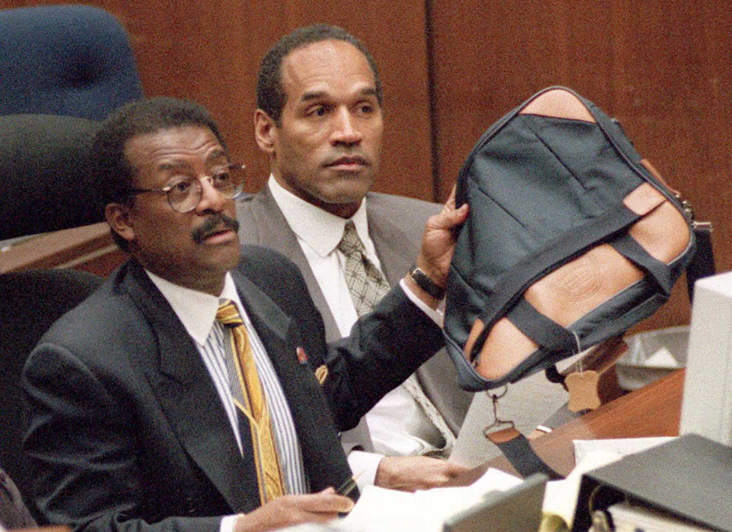 Defense attorney Johnnie Cochran Jr (L) holds up a luggage bag during court session in the O.J. Simpson (R) murder trial. A limousine driver and baggage handler were questioned about Simpson's luggage which he used to travel to Chicago on the night of the double murder. AFP via Getty Images