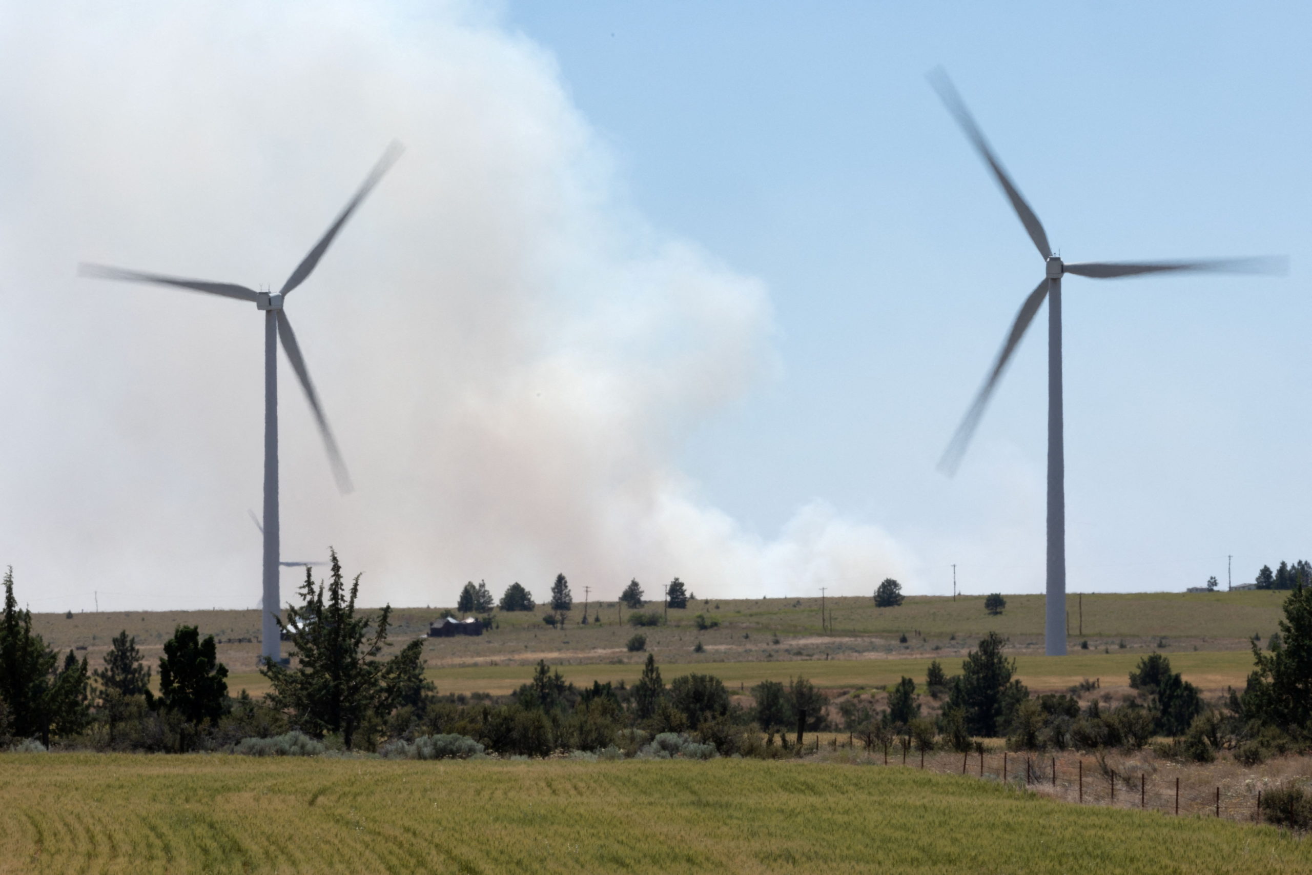 Smoke from the Newell Road Fire near Goldendale, Washington is seen amid wind turbines in Bickleton, Washington, U.S., July 22, 2023. REUTERS/Matt Mills McKnight