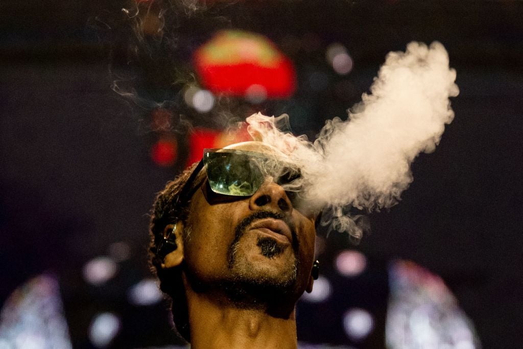 TOPSHOT - US rapper Calvin Cordozar Broadus Jr aka Snoop Dogg blows smoke as he performs on stage at the Accor Arena of Bercy, in Paris, on March 25, 2023. (Photo by Anna KURTH / AFP) (Photo by ANNA KURTH/AFP via Getty Images)