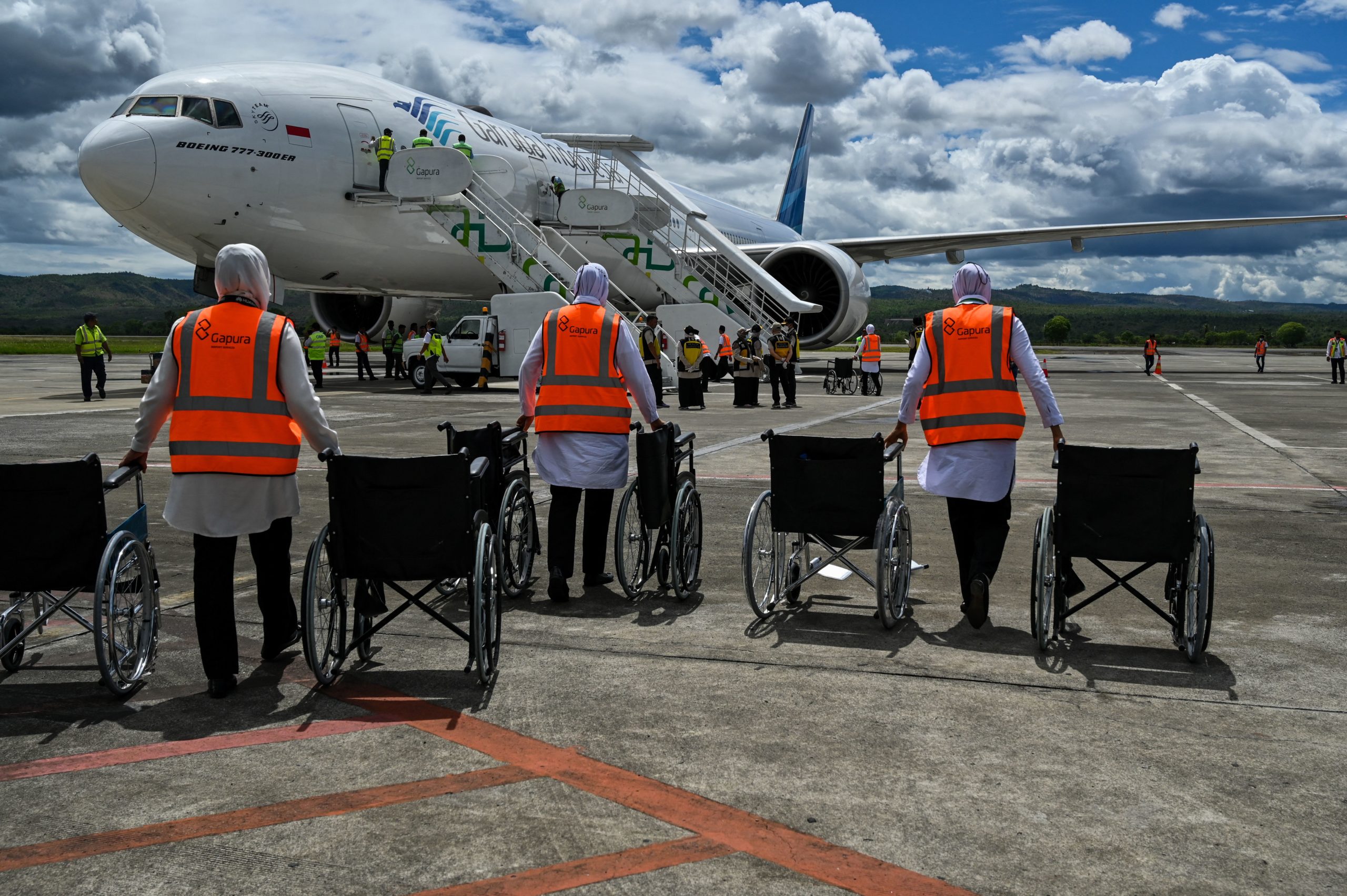 Members of ground staff along with wheelchairs, wait for Indonesian Muslim pilgrims to disembark from a passenger plane upon their arrival at the Sultan Iskandar Muda International Airport in Blang Bintang, Aceh province on July 31, 2023, after performing the annual Hajj pilgrimage. (Photo by CHAIDEER MAHYUDDIN/AFP via Getty Images)