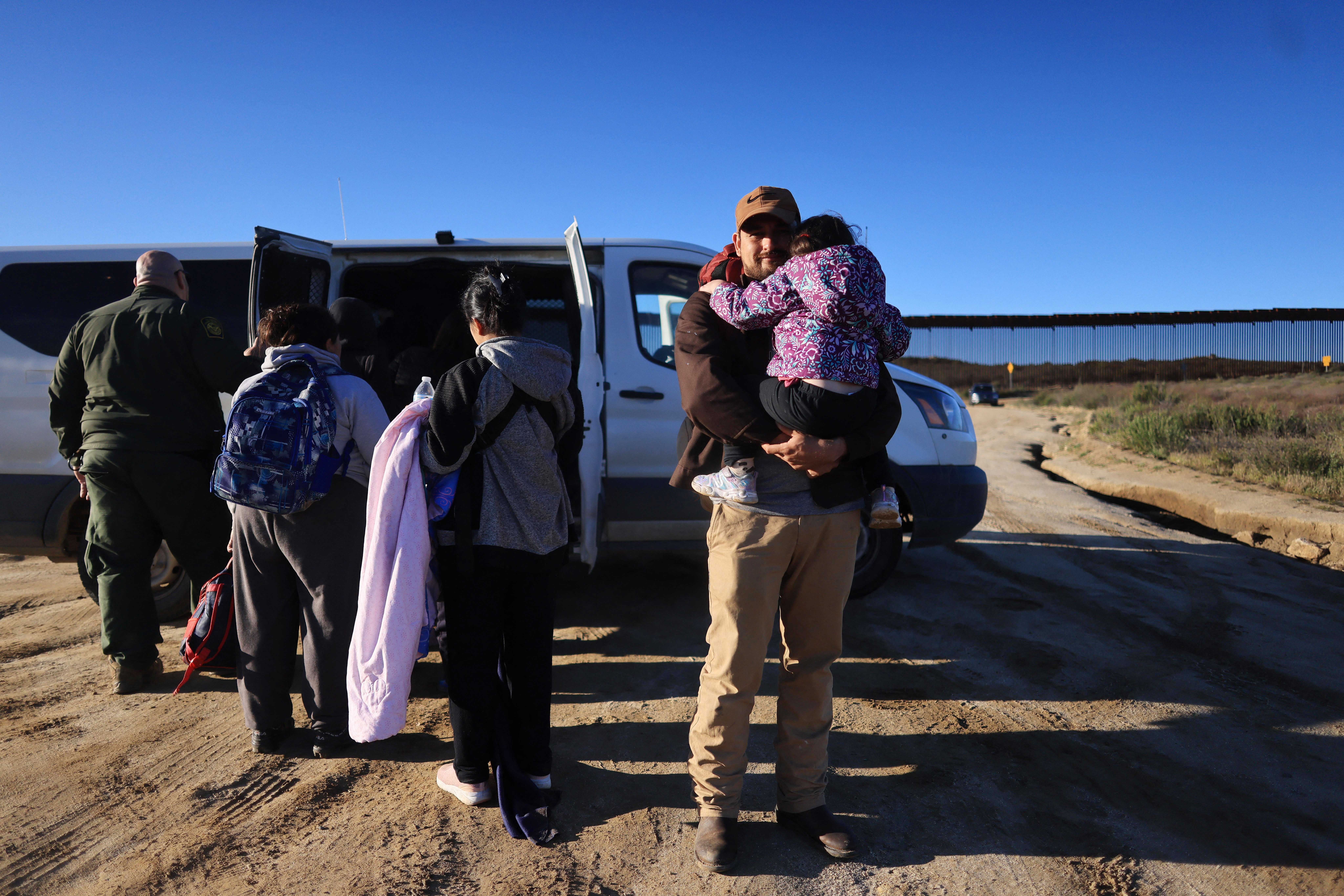 Dozens of asylum seekers wait for US Border Patrol agents near the US-Mexico border in Campo, California, on April 4, 2024. (Photo by DAVID SWANSON/AFP via Getty Images)