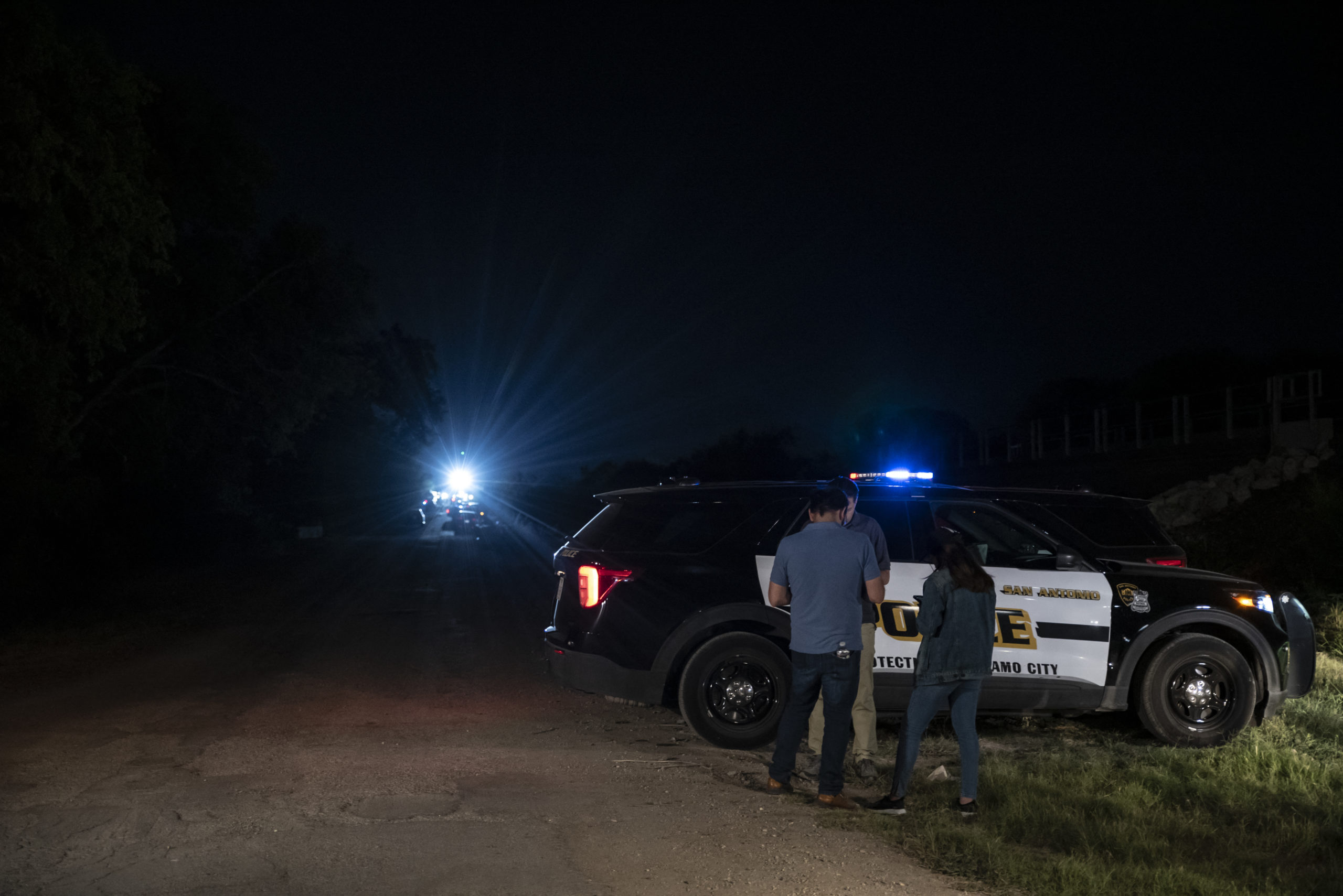 A police car is parked near the scene where a tractor-trailer was discovered with migrants inside outside San Antonio, Texas on June 27, 2022. At least 46 migrants were found dead June 27, 2022 in and around a tractor-trailer that was abandoned on the roadside on the outskirts of the Texas city of San Antonio. (Photo by SERGIO FLORES/AFP via Getty Images)