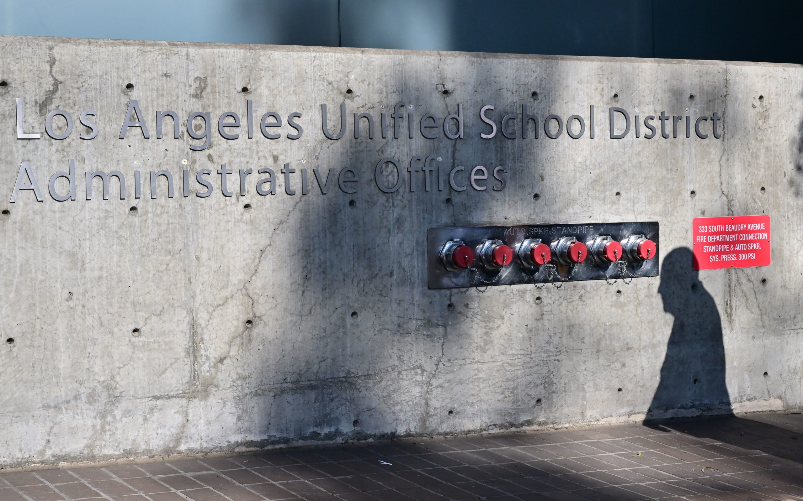 The shadow of a pedestrian is seen walking past the headquarters of the Los Angeles Unified School District on October 3, 2022 in Los Angeles, California. - LAUSD Superintendant ALberto Carvalho remains firm on Monday on his refusal to pay a ransom demanded by an international hacking syndicate, days after hacked data from the school district was posted on the dark web. A hacking syndicate known as Vice Society sent a ransom demand to the school district last week setting an October 3 deadline to pay the unspecified ransom with threats to release more hacked data online if payment is not met.(Photo by FREDERIC J. BROWN/AFP via Getty Images)