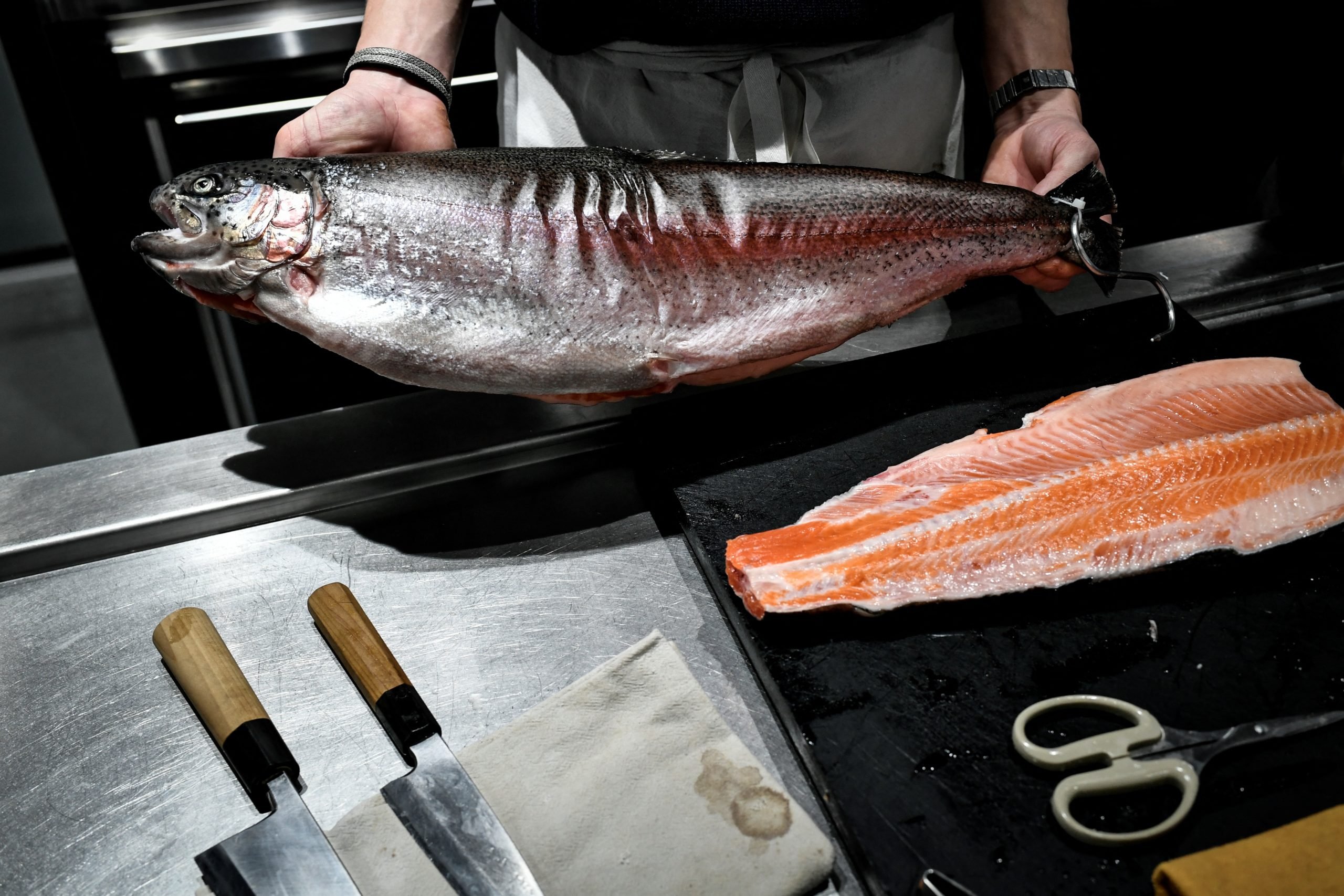 An employee shows a trout getting prepared for sashimi at the Viot fishershop in Paris on February 15, 2024. Salmon is the second most consumed seafood product, behind tuna, with an annual average of 2.7 kg per capita, according to France Agrimer, the French national agency for agriculture and fisheries. Arthur Viot, a 28-year-old fishmonger has replaced it in his stalls with trout, which he serves as sashimi. (Photo by STEPHANE DE SAKUTIN/AFP via Getty Images)