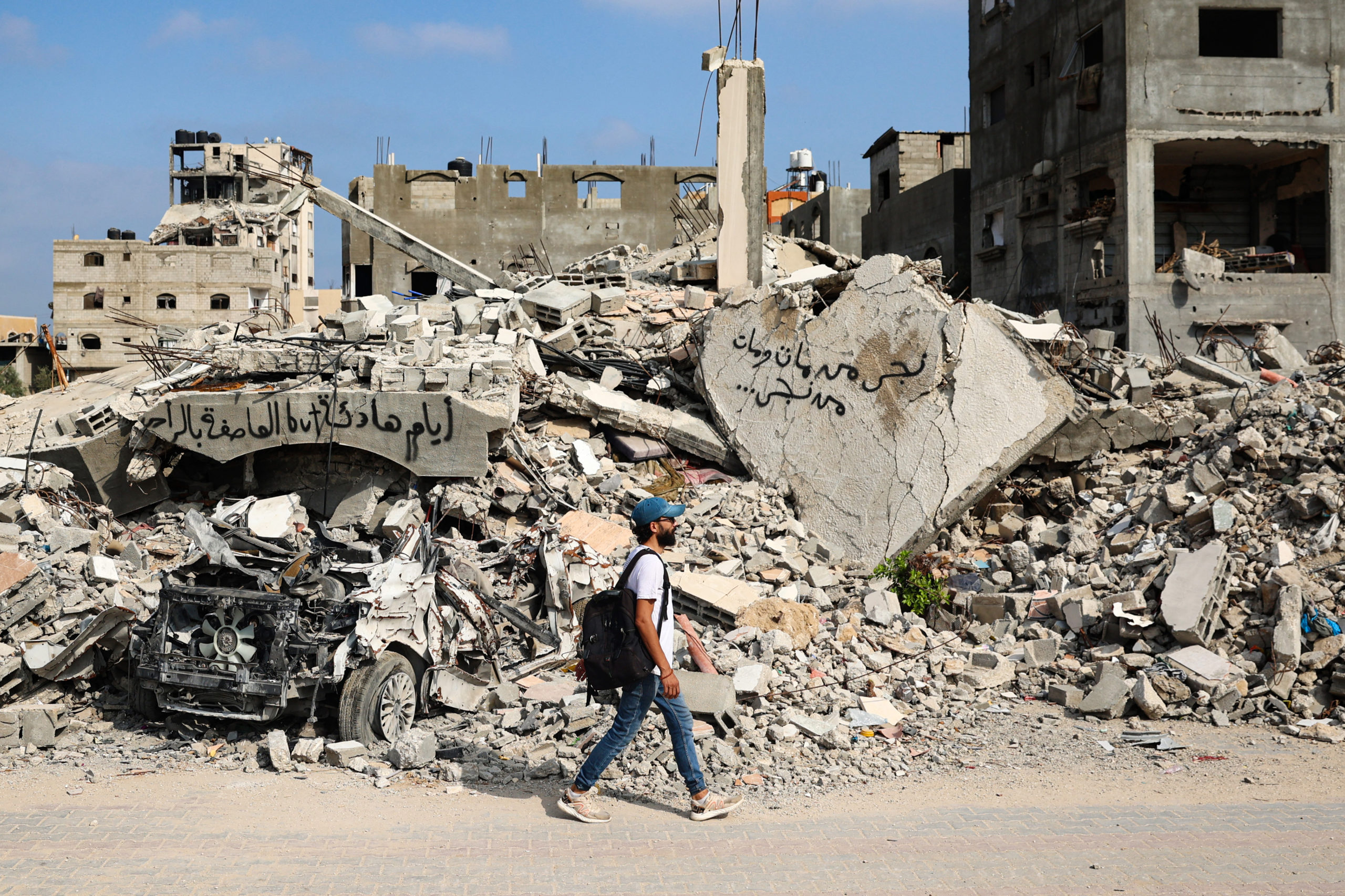 A Palestinian man walks next to debris, tagged with graffiti, after an overnight Israeli strike in al-Bureij camp in the central Gaza Strip on June 3, 2024, amid the ongoing conflict between Israel and the Palestinian Hamas militant group. (Photo by EYAD BABA/AFP via Getty Images)