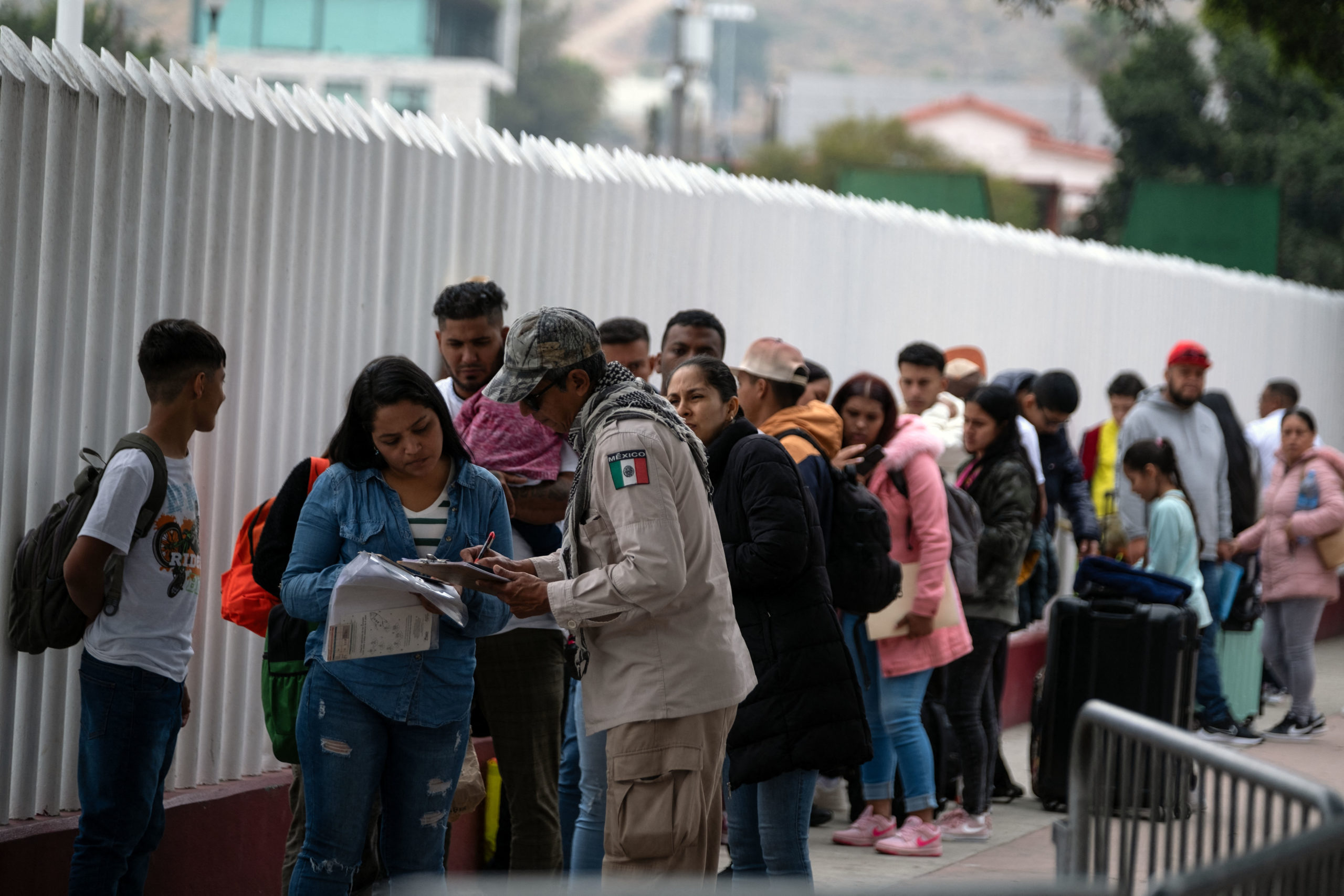 A Mexican migration official checks the papers of asylum seekers at the El Chaparral crossing port before they attend their appointment with US authorities at the US-Mexico border in Tijuana, Baja California State, Mexico, on June 5, 2024. President Joe Biden said Tuesday he had ordered sweeping new migrant curbs to 