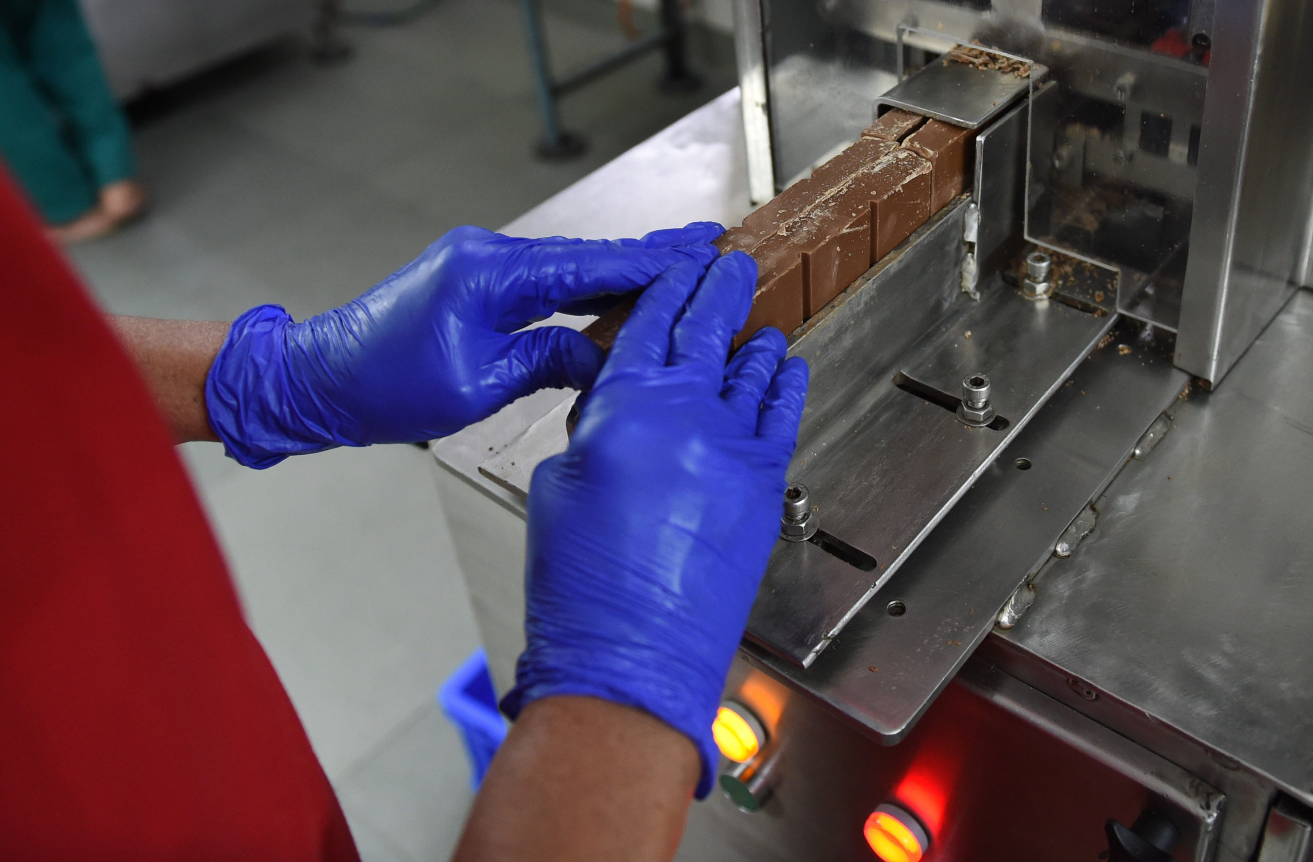 An Indian factory worker cuts chocolate bars with a chocolate bar cutting machine on an assembly line at the Havmor Ice Cream plant in Naroda, near Ahmedabad, on April 5, 2018. South Korea's Lotte Confectionery Group in 2017 took over India's Havmor Ice Cream, which produces some 200,000 litres of ice cream daily from its Naroda plant. (Photo credit SAM PANTHAKY/AFP via Getty Images)