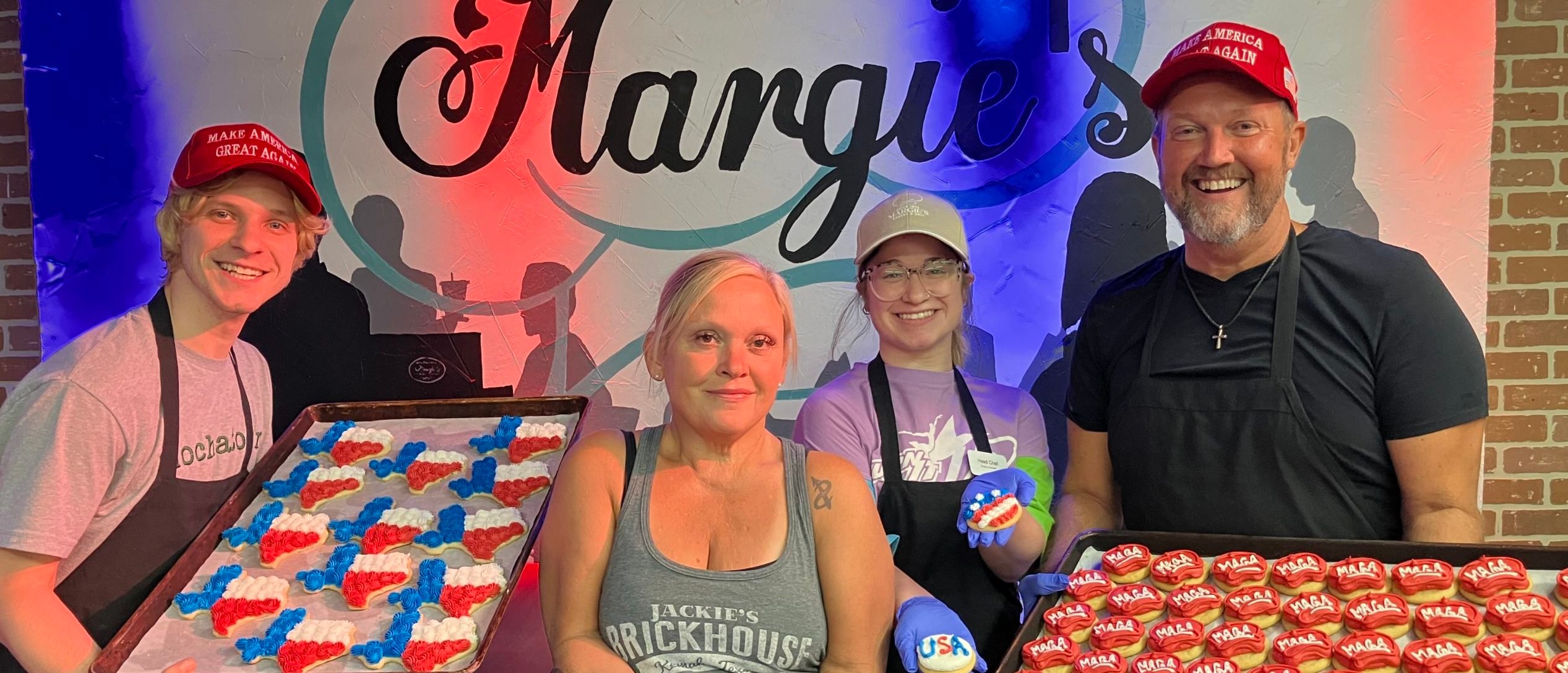 Employees of Margie's Bakery & Deli pose with their cookies in MAGA hats.