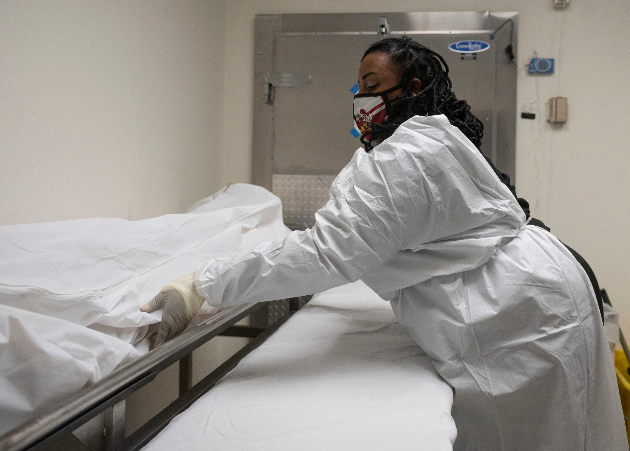 Funeral home transporter Morgan Dean-McMillan prepares to transport a suspected Covid-19 positive body in a hospital's morgue in Baltimore, Maryland on December 23, 2020 during the Covid-19 pandemic. The United States surpassed 18 million reported Covid-19 cases on Monday, figures from Johns Hopkins University showed, as the virus surges nationwide. When it comes to vaccination priority, long-term care residents and health workers are at the front of the line. Maryland crematorium owner Dorota Marshall hopes that her workers going to do pickups and regularly entering hospitals, hospices, nursing homes and residences, get the vaccine in the next round. Marshall says "We visit homes where people recently died from Covid or family members are positive, so absolutely I think we are front line workers." (Photo by ANDREW CABALLERO-REYNOLDS/AFP via Getty Images)